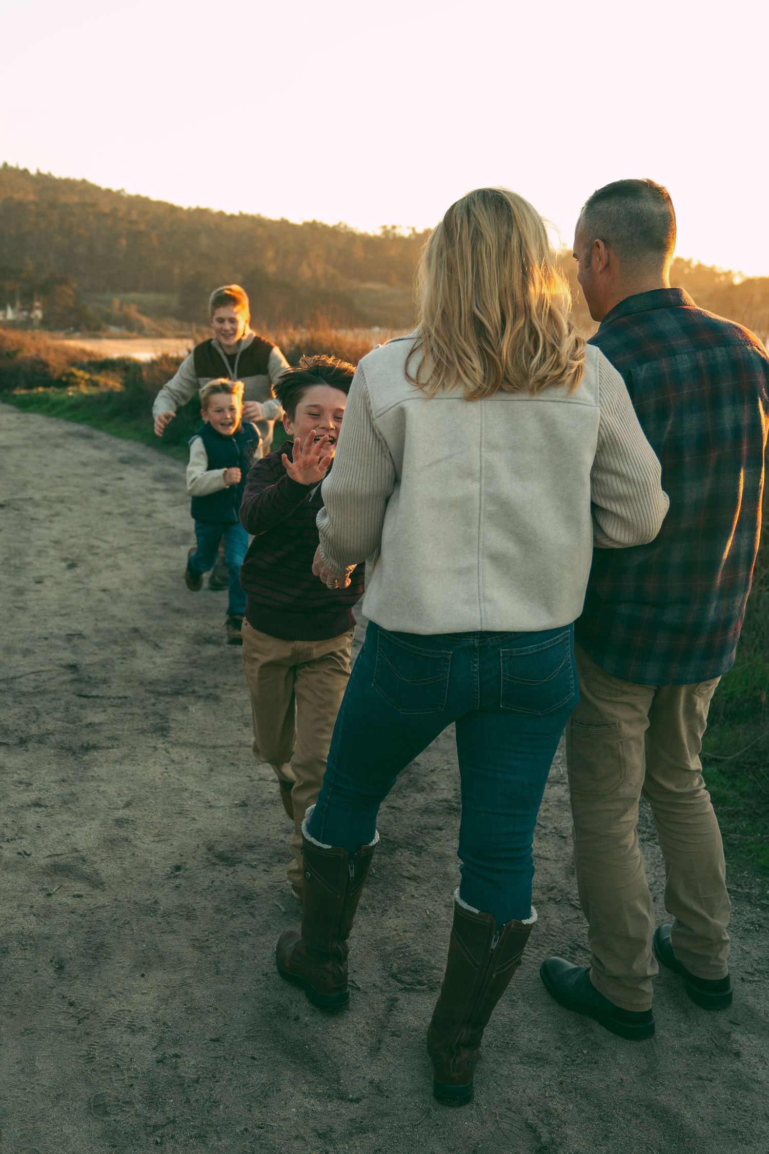 A sequence of photos showing a proposal moment at sunset on a beach with loved ones capturing the special occasion.