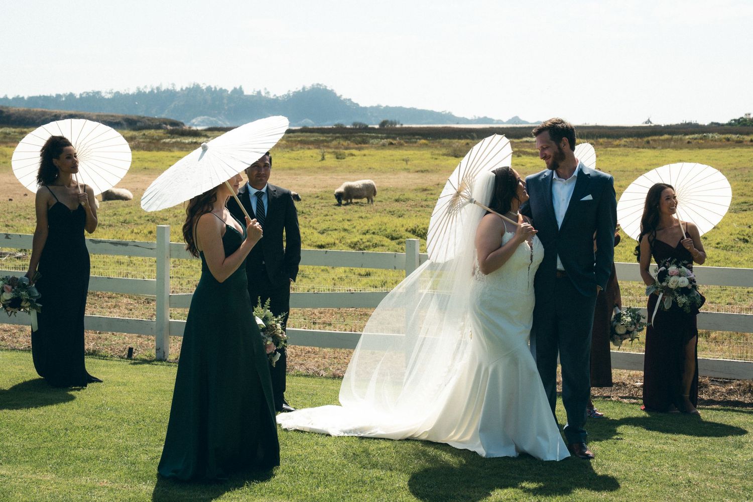 Outdoor wedding ceremony setup with scenic mountain views and guests gathered on grassy field.