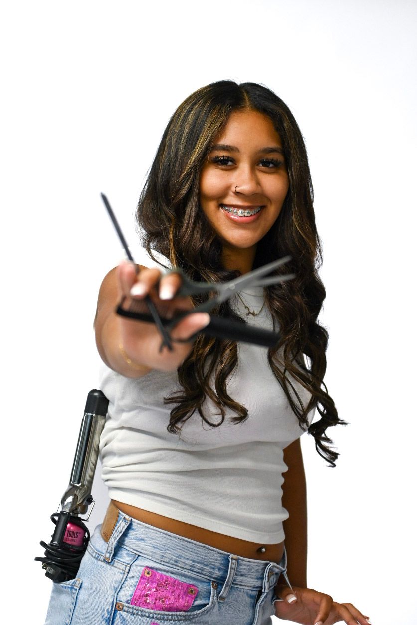 High School Senior posing with cosmetology equipment to show her interest. Scissors, comb, curling iron