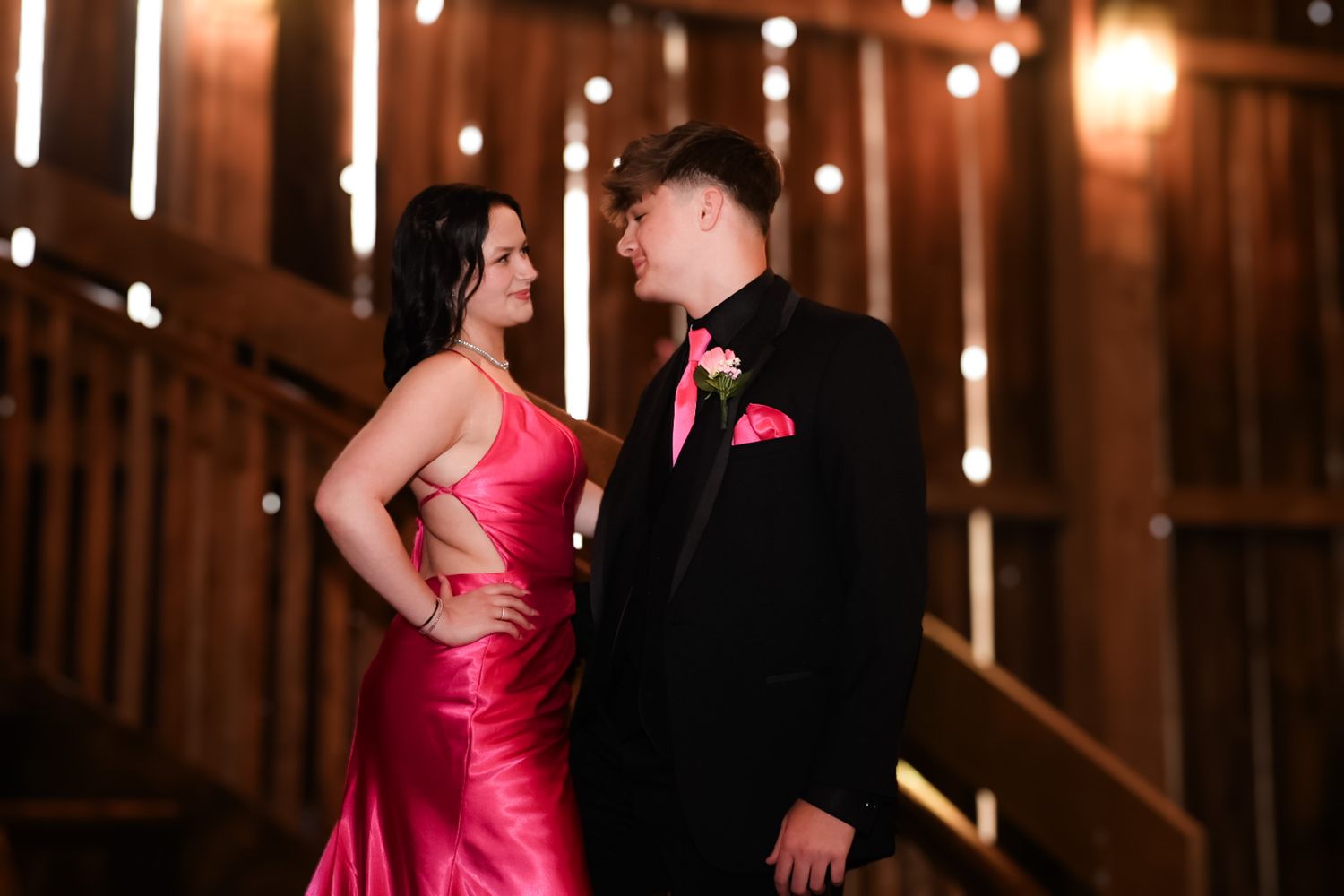 Dates for homecoming look at each other with twinkling lights in the background