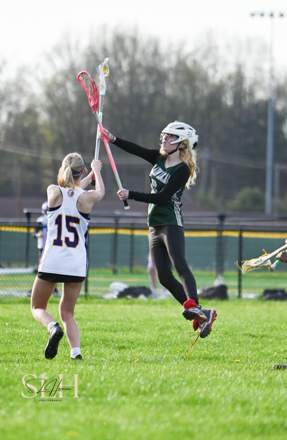 Girl leaps into air to catch a lacrosse ball in the game