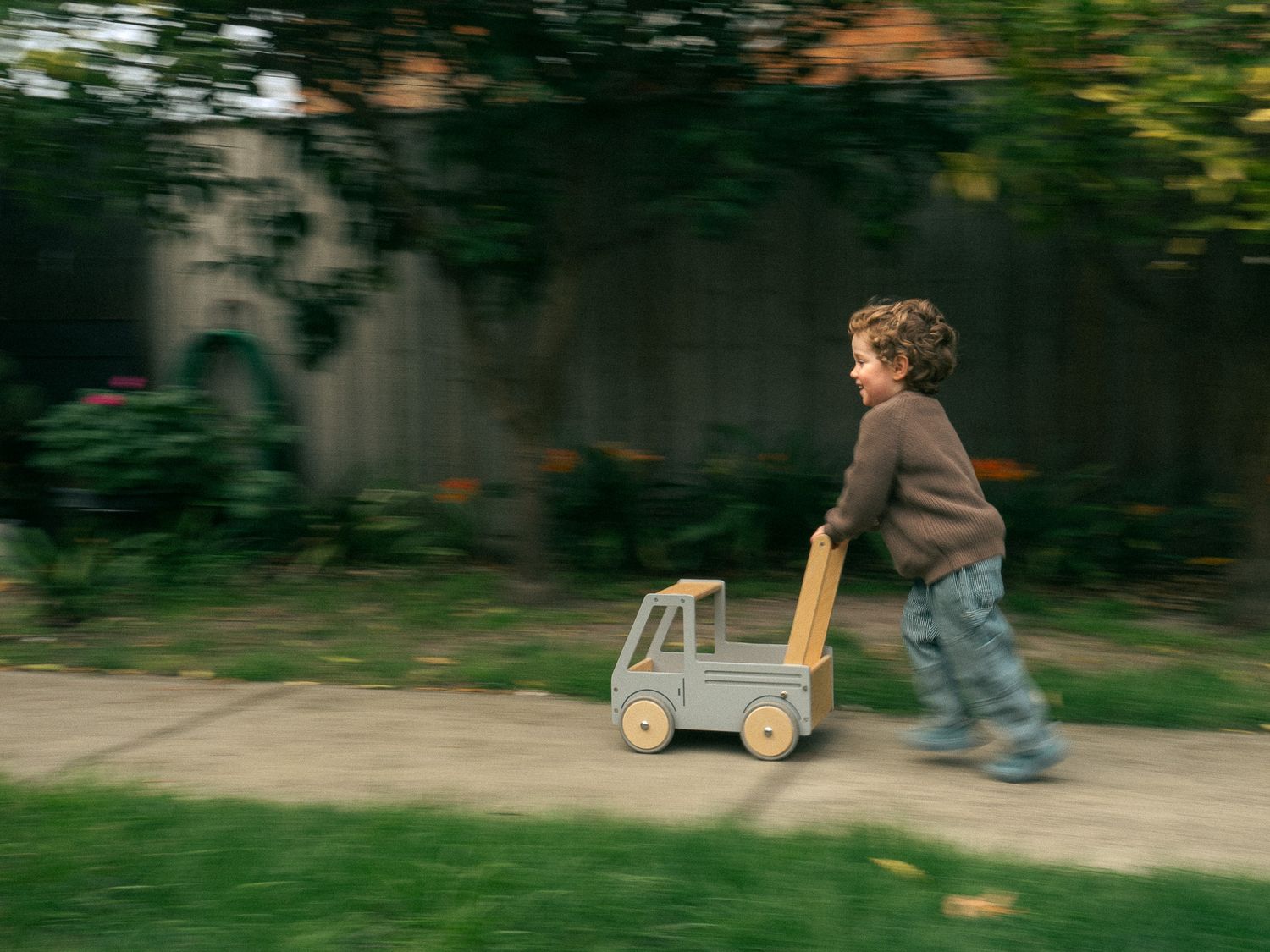 Motion blur sequence of children playing with a wooden wagon outdoors in their Melbourne home.