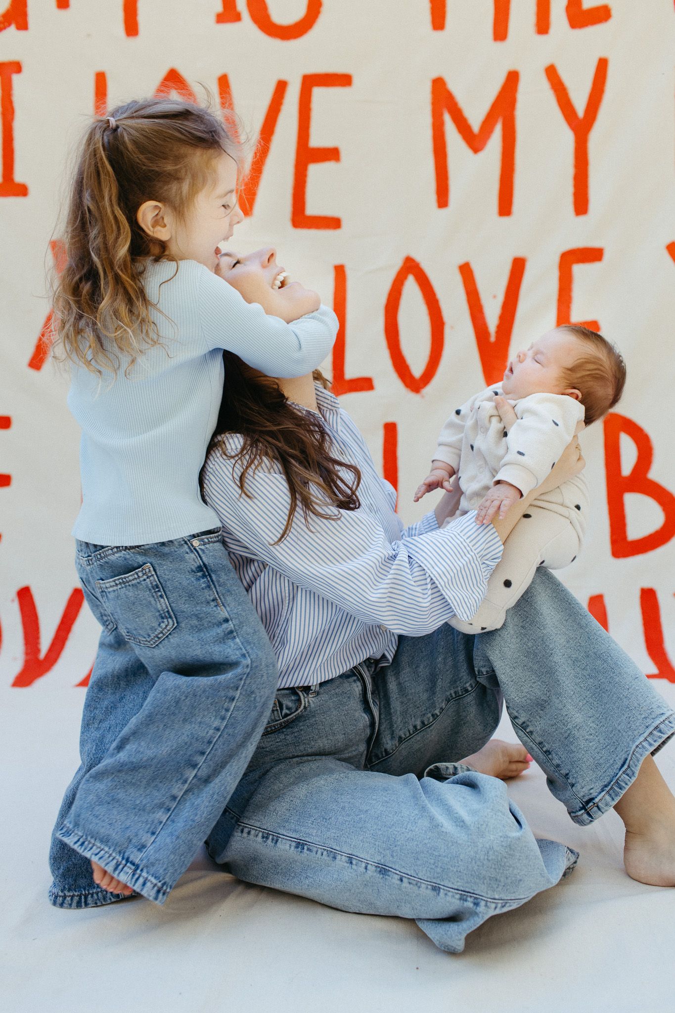 A mother and her two children playing infront of a mothers day photoshoot setup.