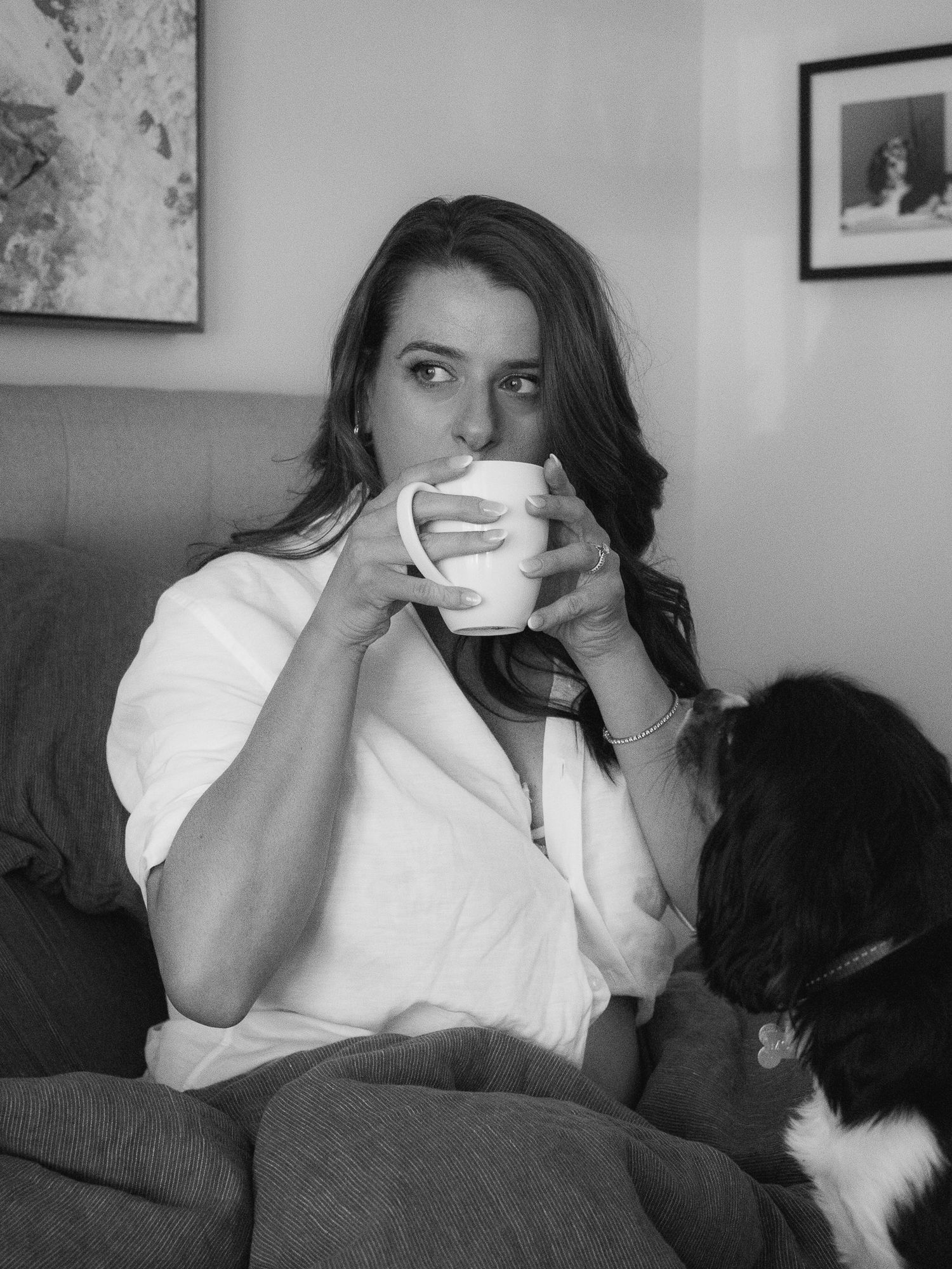 A series of four black and white photos showing someone drinking from a coffee mug while sitting on a couch.