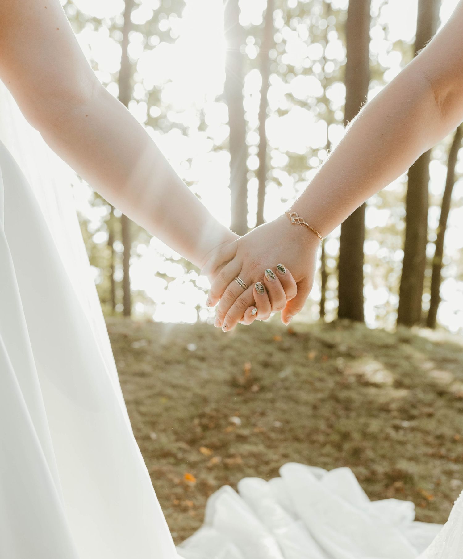 Close-up of white wedding dress flowing in gentle breeze against forest backdrop.