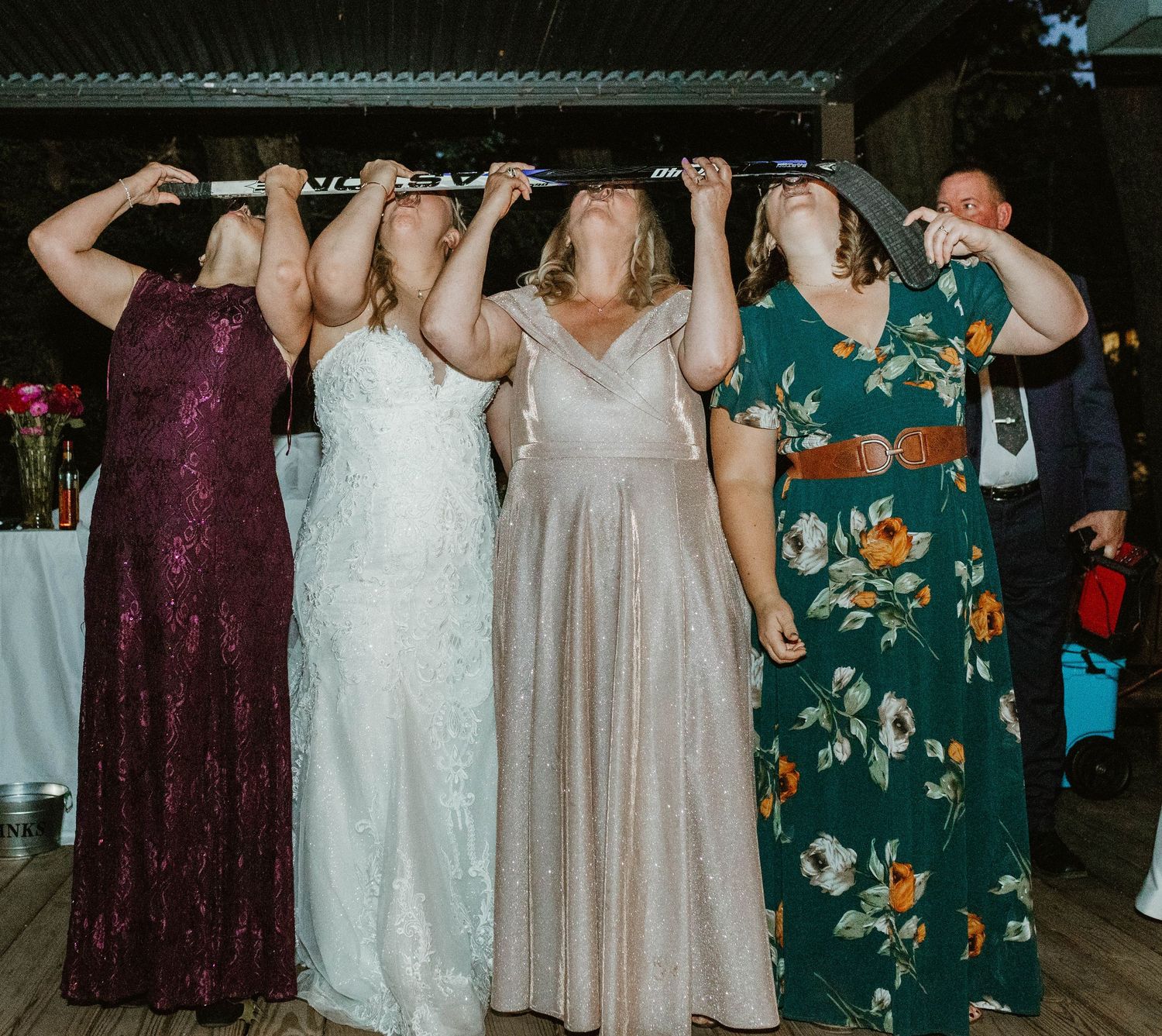 Wedding party members in mix of colorful dresses dance together during reception celebration.