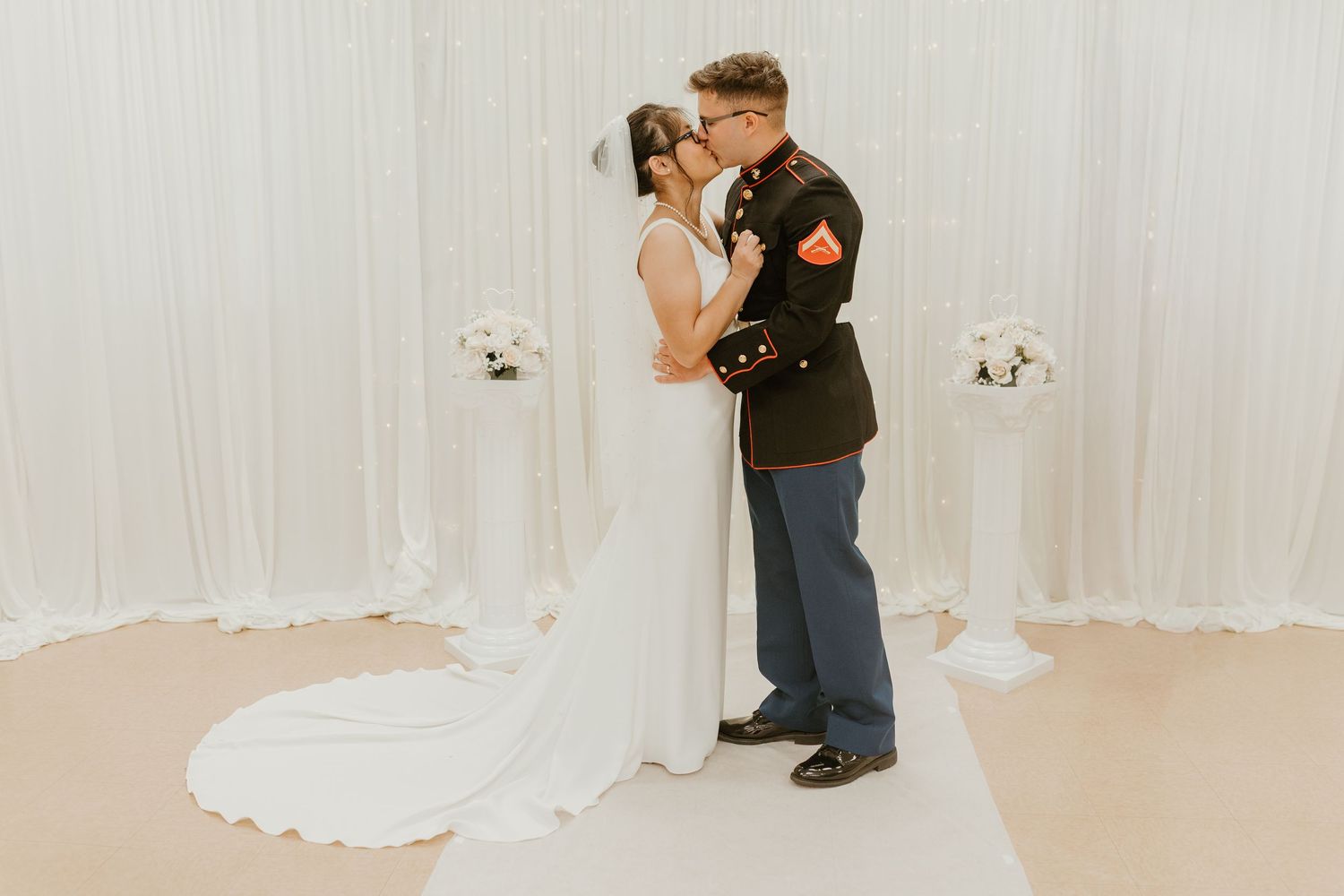 A couple shares their first dance in an elegant white-draped wedding reception venue.