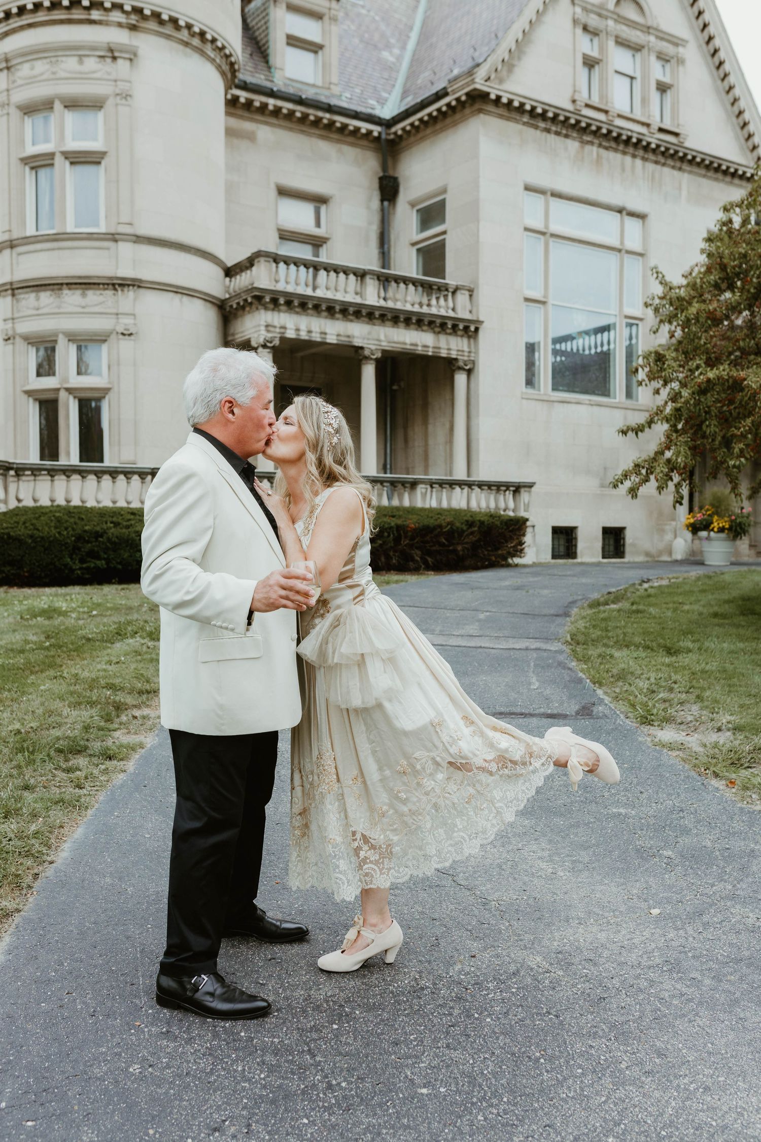 A couple sharing a romantic moment outside a grand historic mansion on their wedding day.