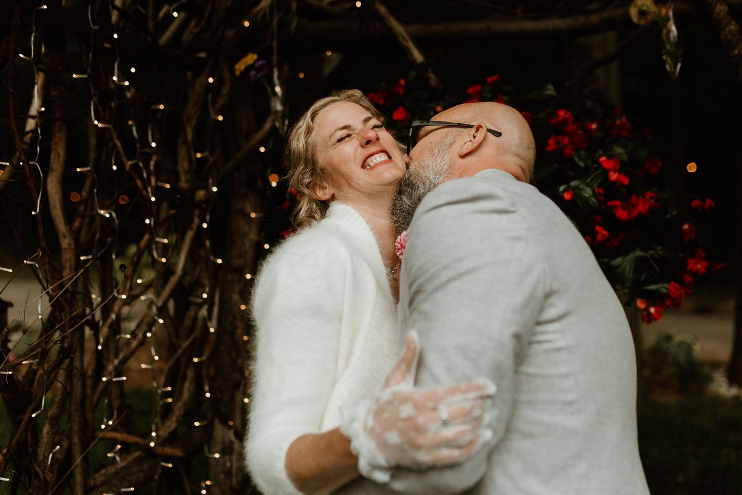 Romantic evening dance moment at wedding reception with twinkle lights in background.