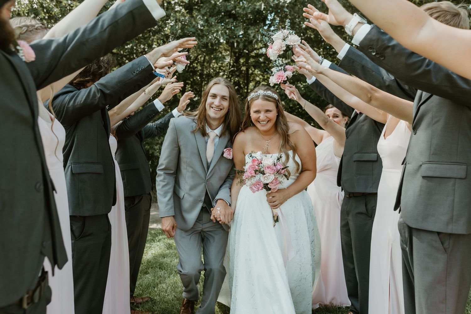 Wedding party forms a tunnel of raised arms for the newlyweds to walk through.