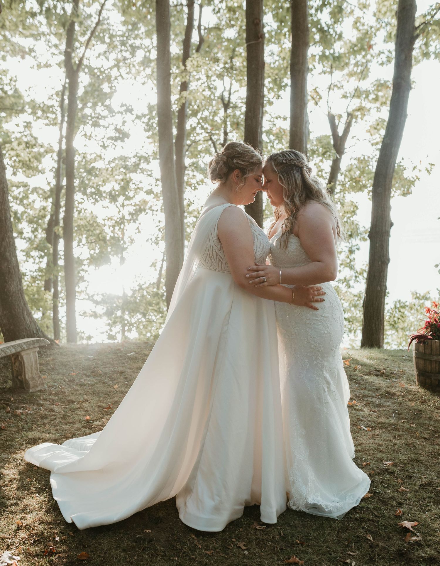 Ethereal forest wedding photos with white dresses against sunlit trees.