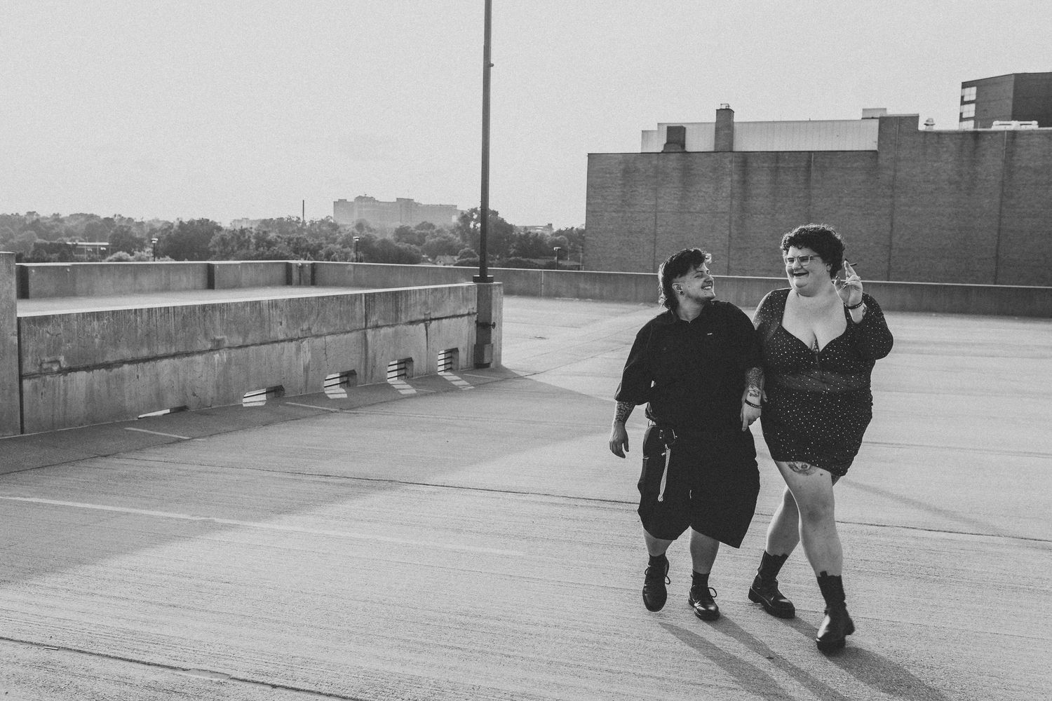 Two people walking arm in arm on a rooftop parking lot in a black and white urban photo.