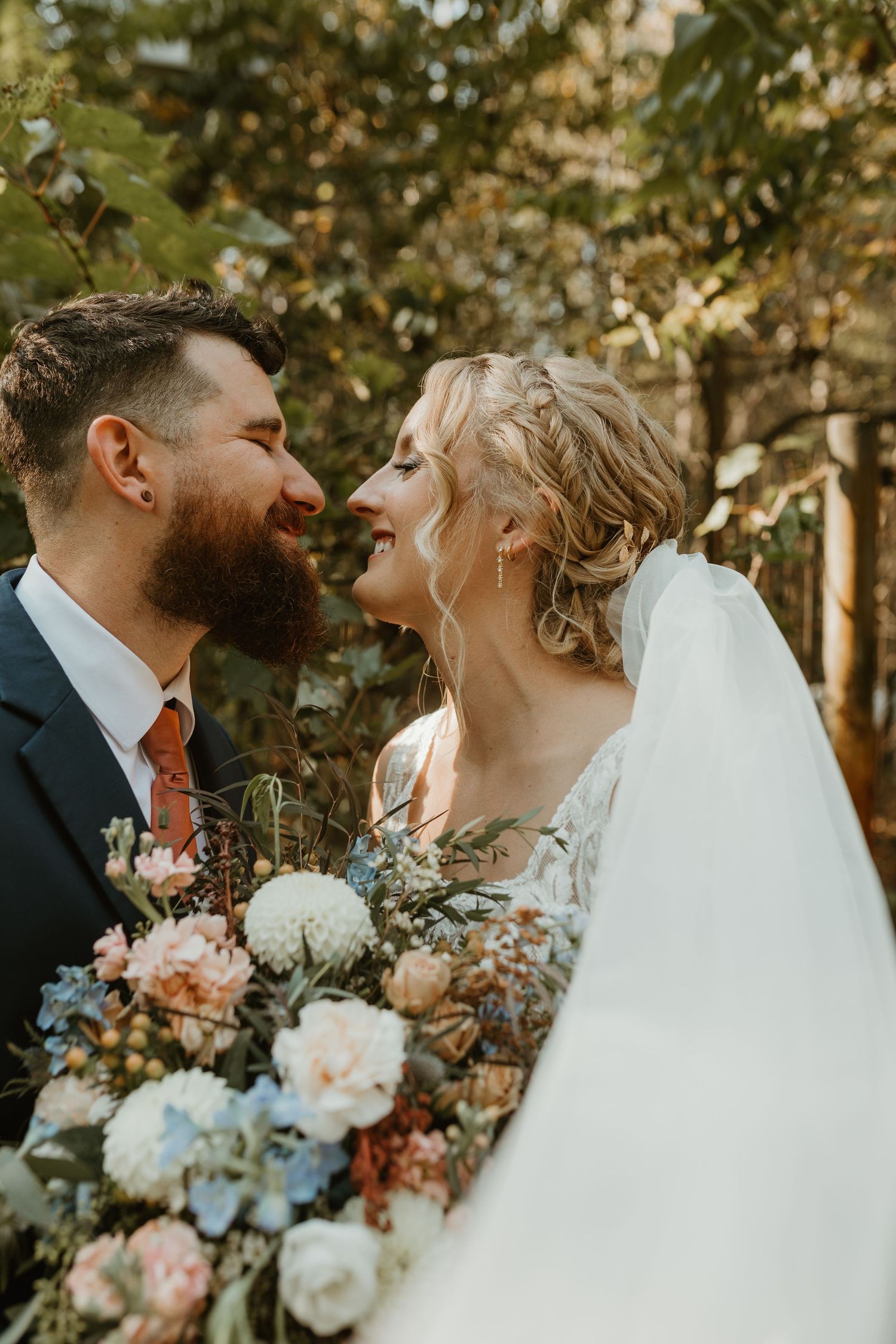 Intimate wedding couple moment captured in natural lighting with soft pastel florals.