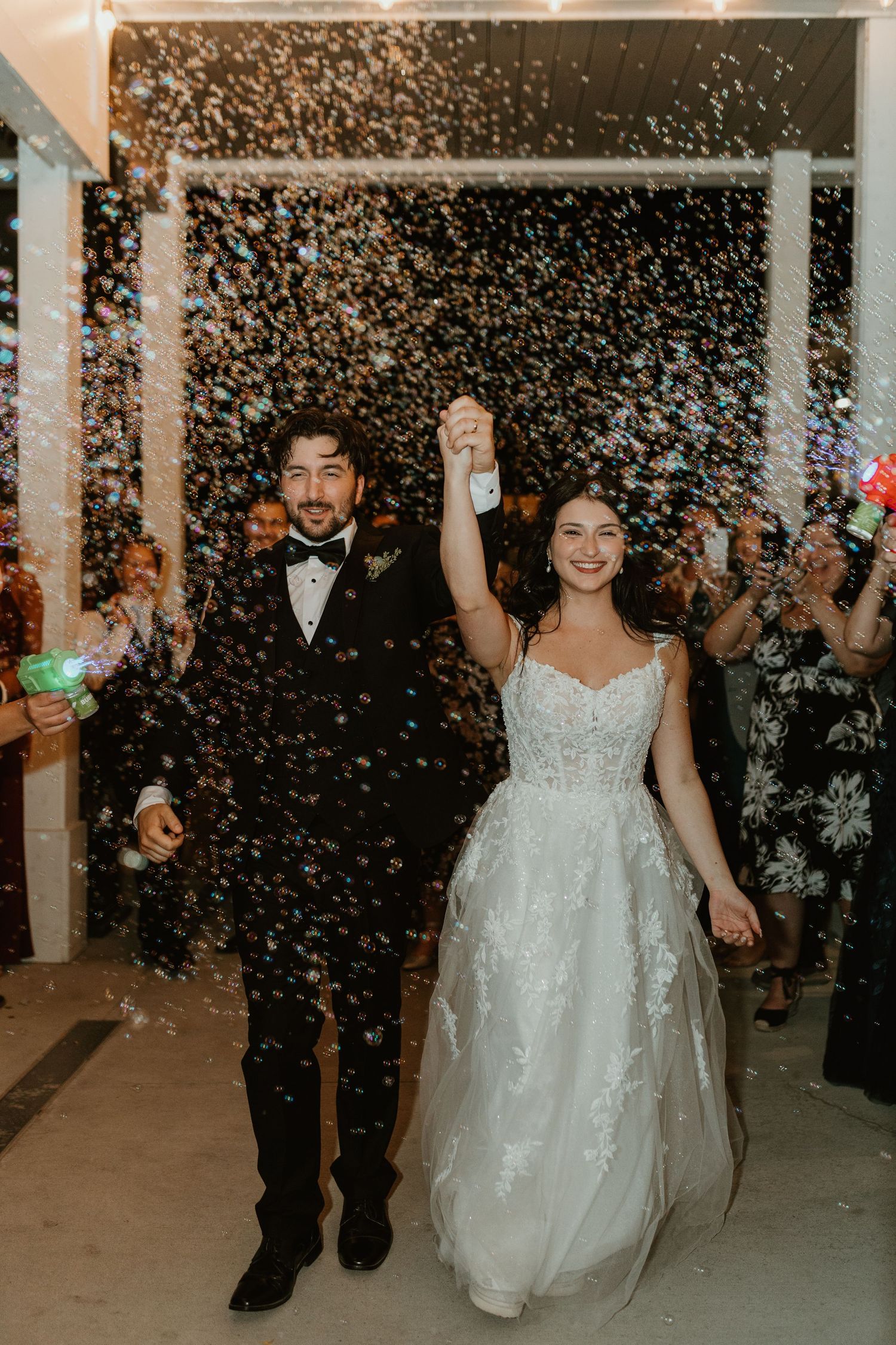 Wedding celebration exit with confetti shower and joyful dancing in an indoor reception space.