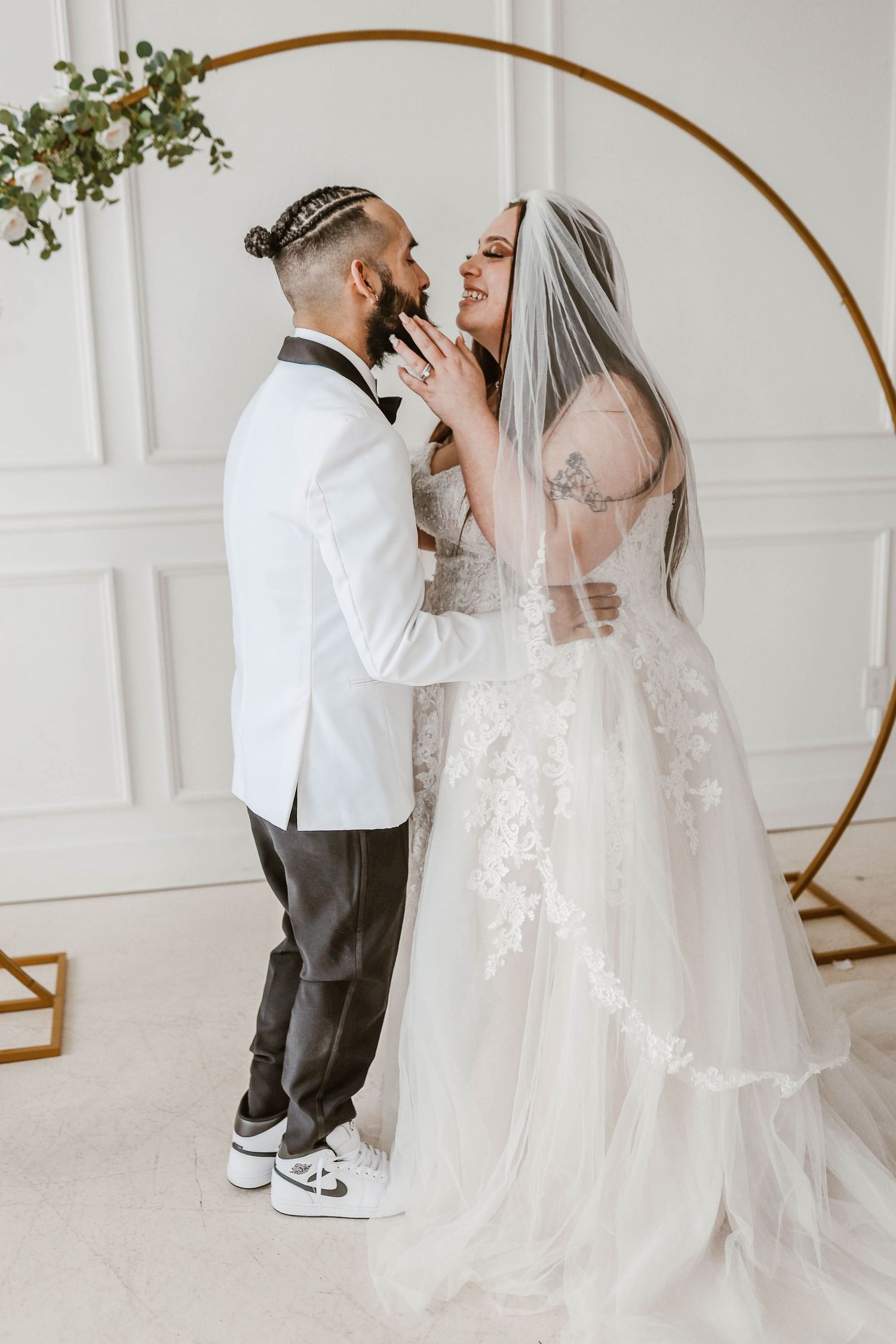 A joyful couple sharing an intimate moment under a modern circular wedding arch.