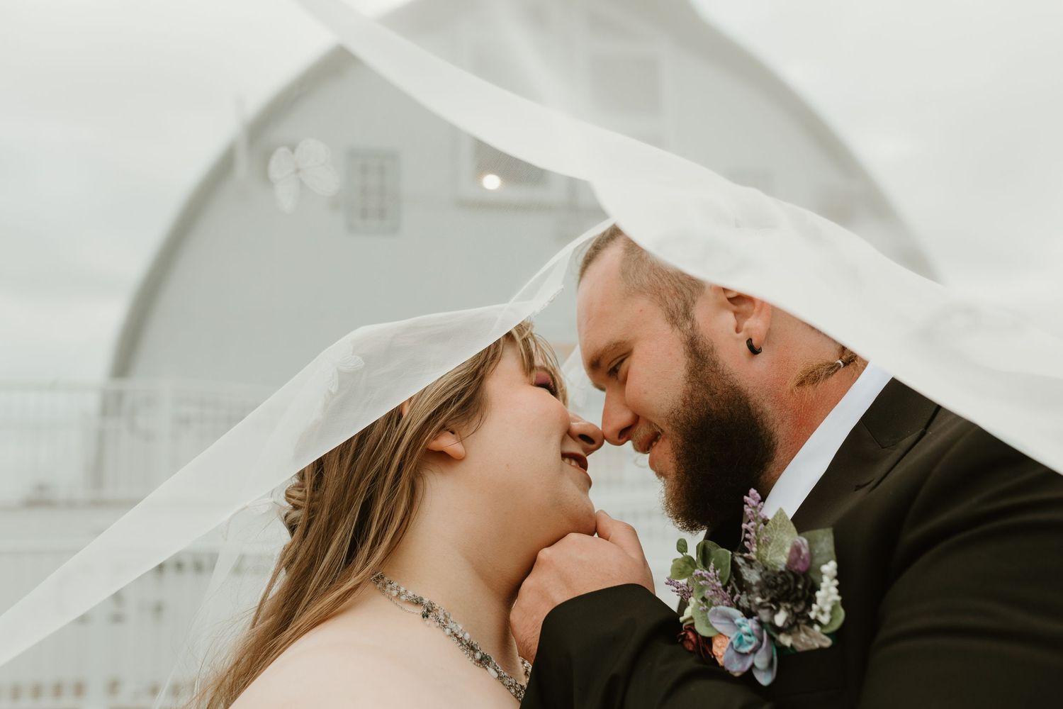 Close-up romantic wedding portrait under a white veil.