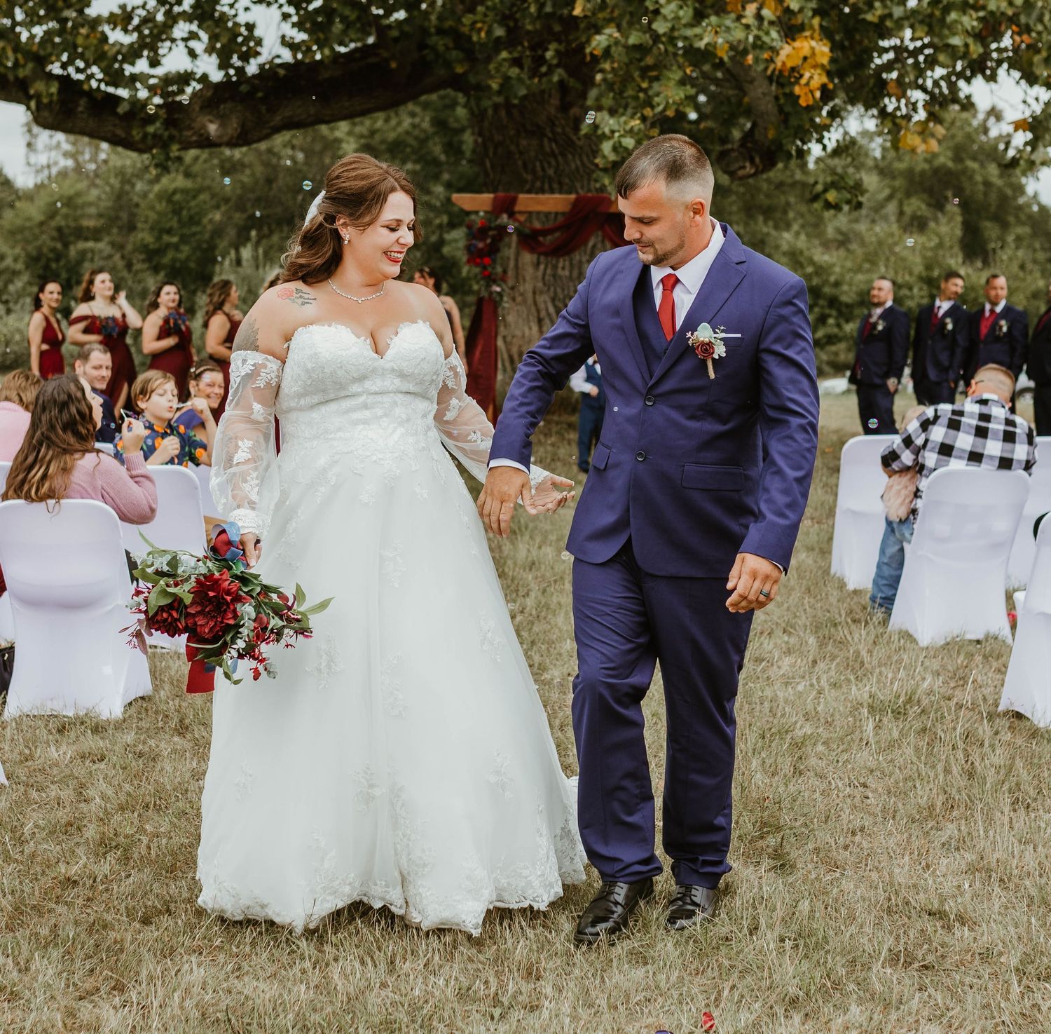 Wedding party poses together on grassy lawn in navy and white attire.