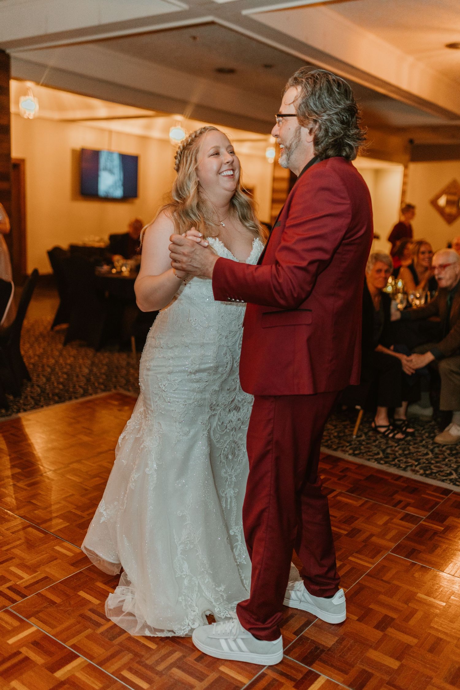 A couple shares their first dance on a parquet floor at their wedding reception.