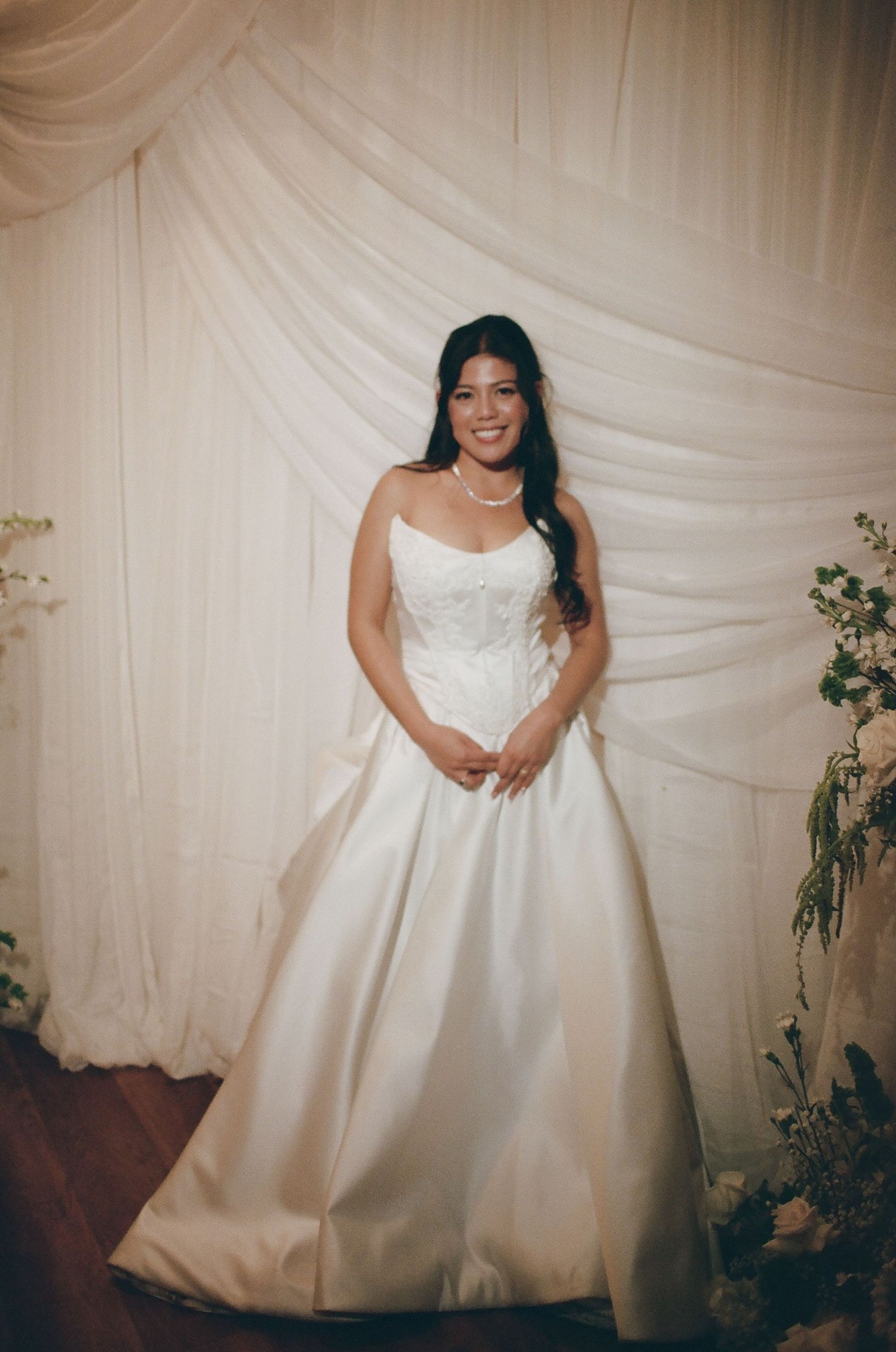 A series of wedding photos showing a bride in a white ballgown dress posing against a draped fabric backdrop.
