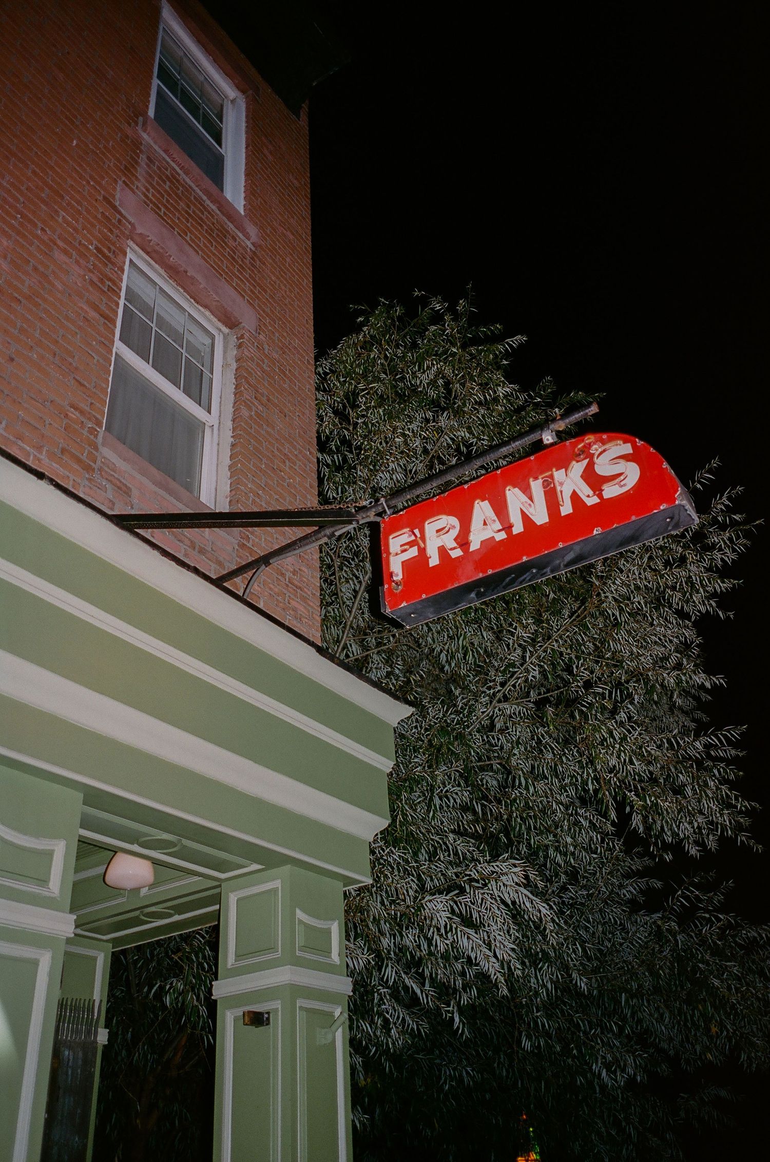 A sequence of nighttime photos showing a red illuminated sign for 'FRANKS' on the exterior of a brick building.