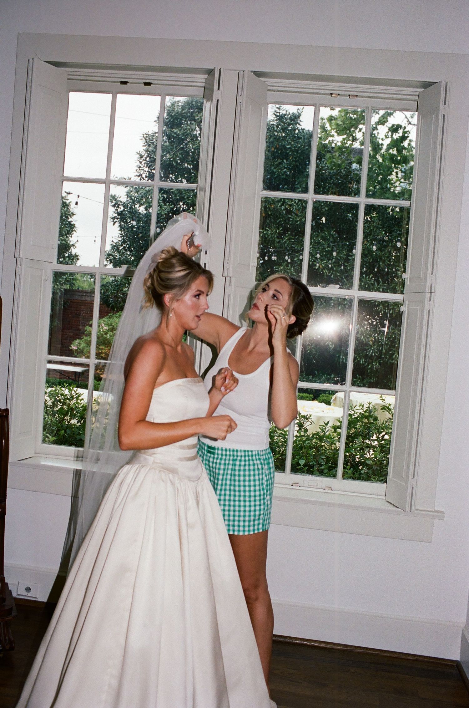 Two people sharing a playful moment in a bright room with one wearing a wedding dress.