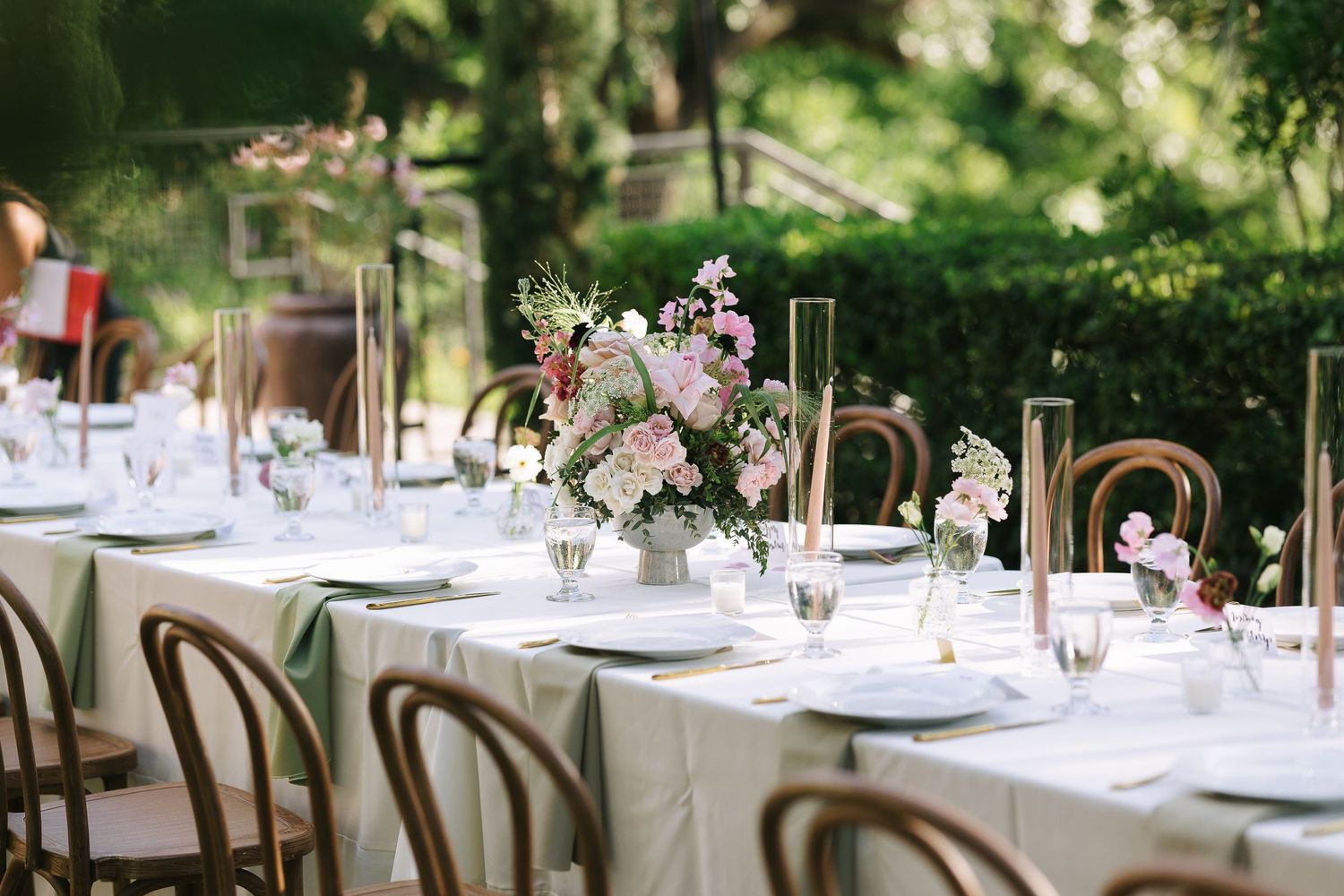 Outdoor wedding reception tables arranged with elegant place settings and floral centerpieces.