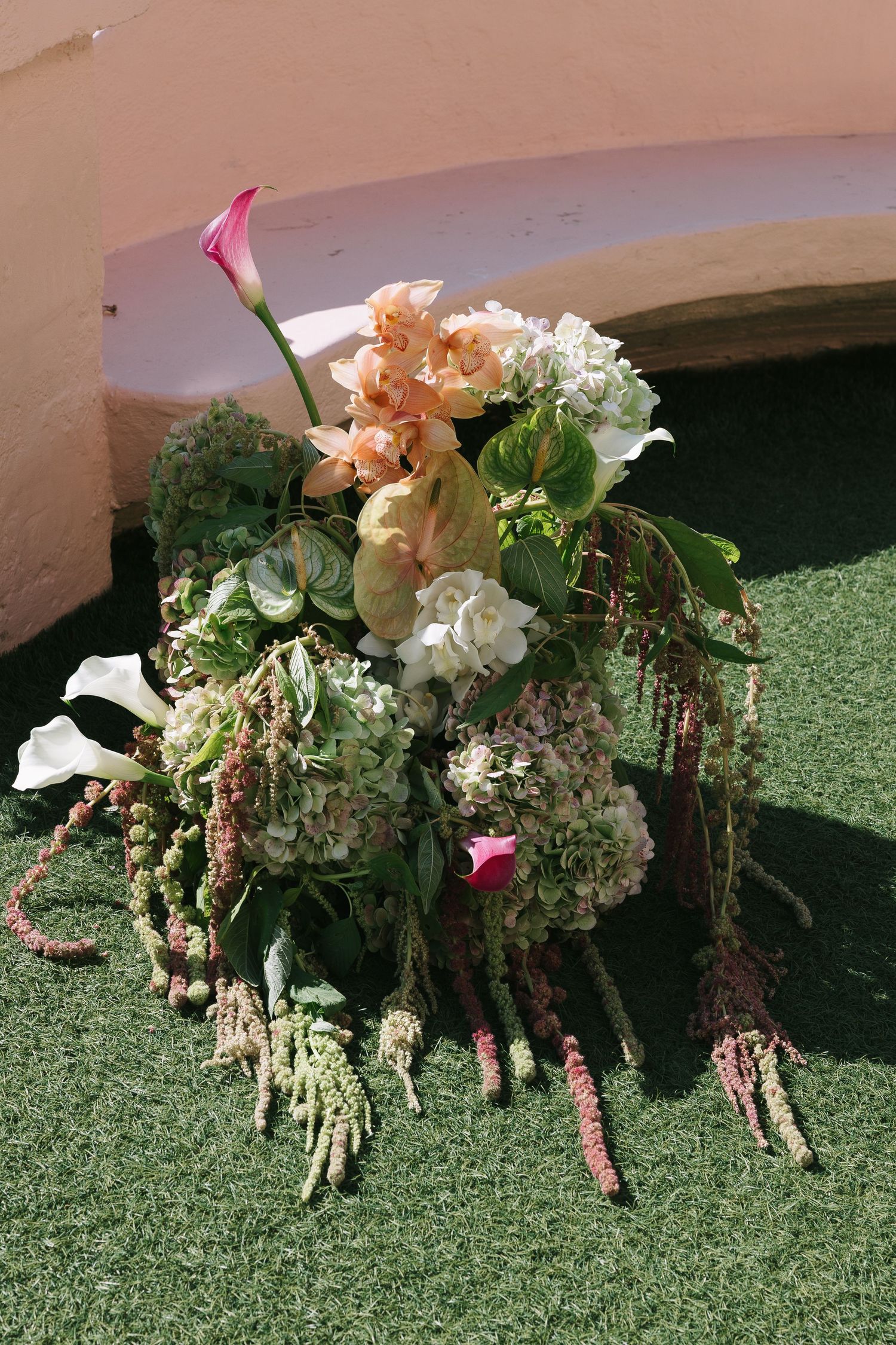 Beautiful floral arrangements with peach and white flowers displayed on green grass at wedding venue.