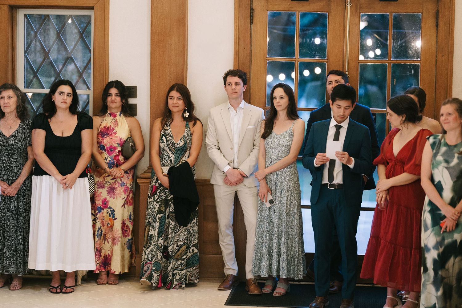 A group of guests in formal attire standing together at an indoor event.