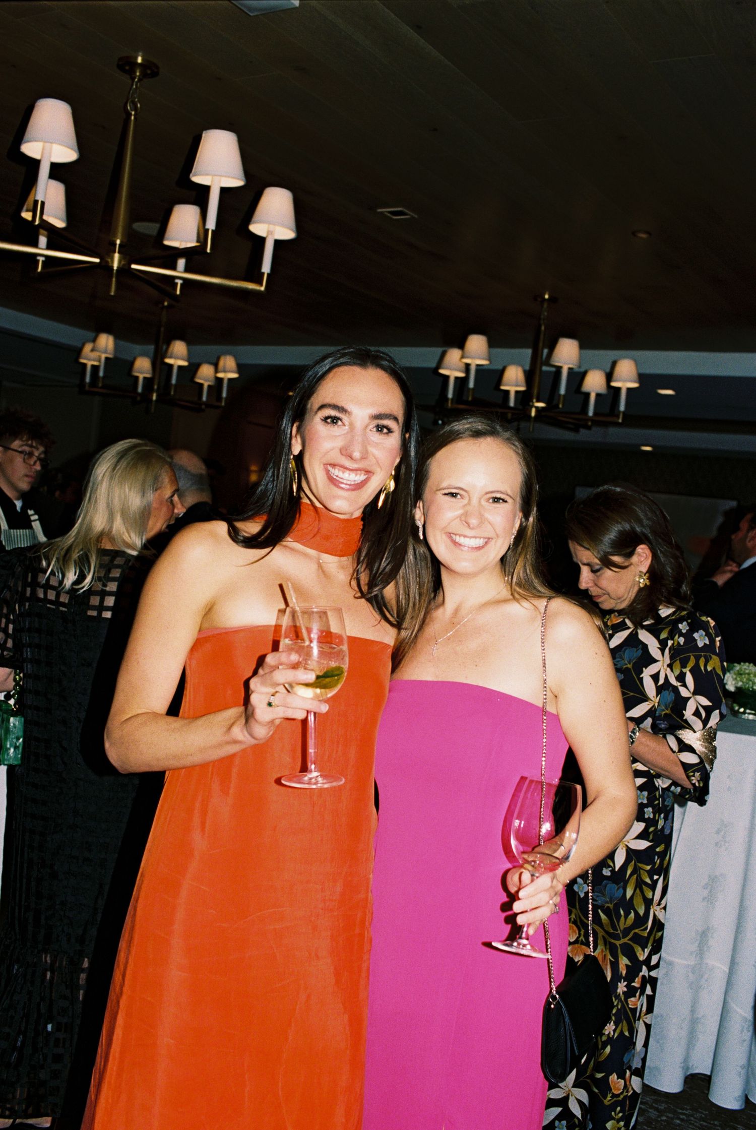 Festive party scene with colorful dresses and raised glasses in celebration.