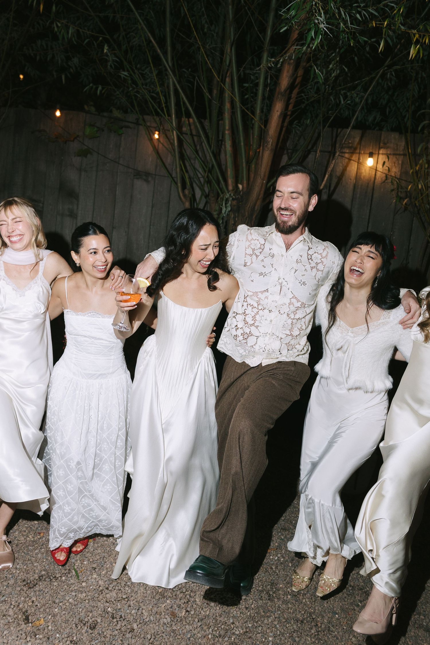A group of people in white outfits dancing and celebrating at a nighttime outdoor party.