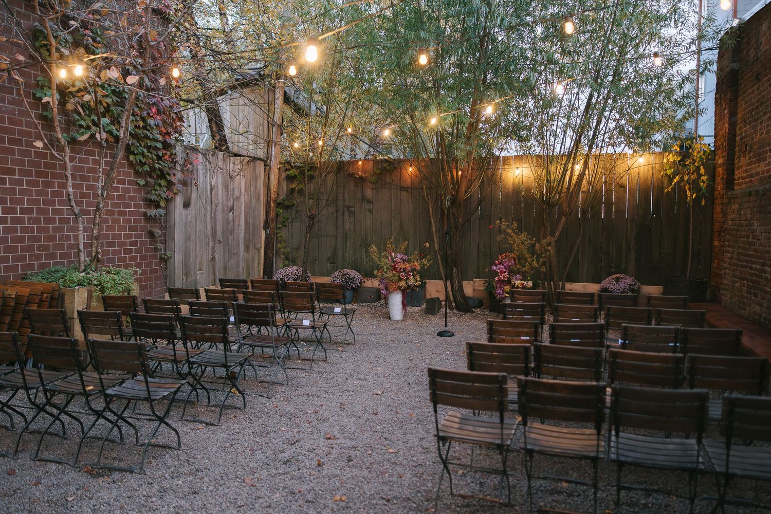 Outdoor wedding venue with rows of wooden chairs and string lights creating a romantic atmosphere.