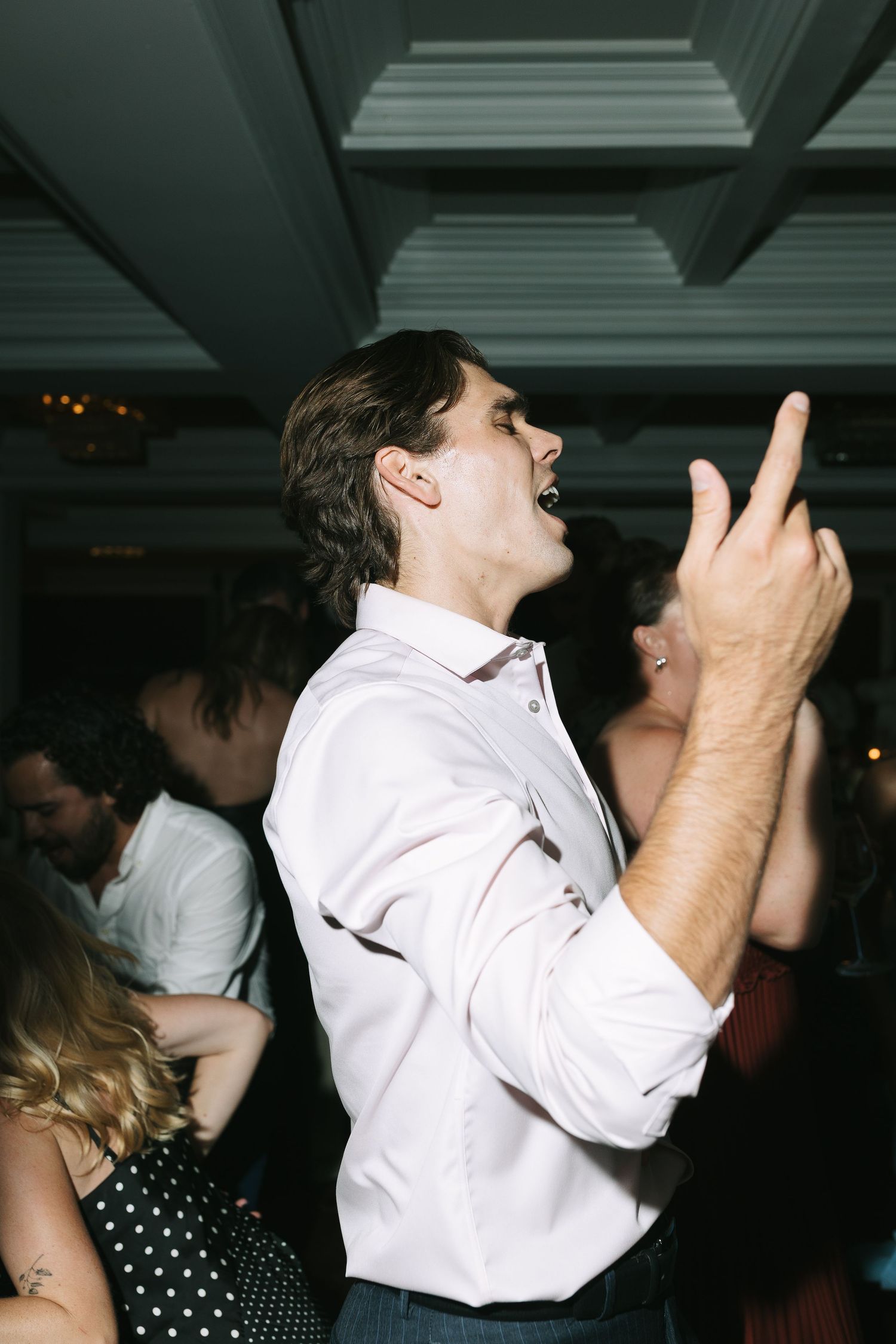 Energetic dance moves captured at a dimly lit formal celebration.