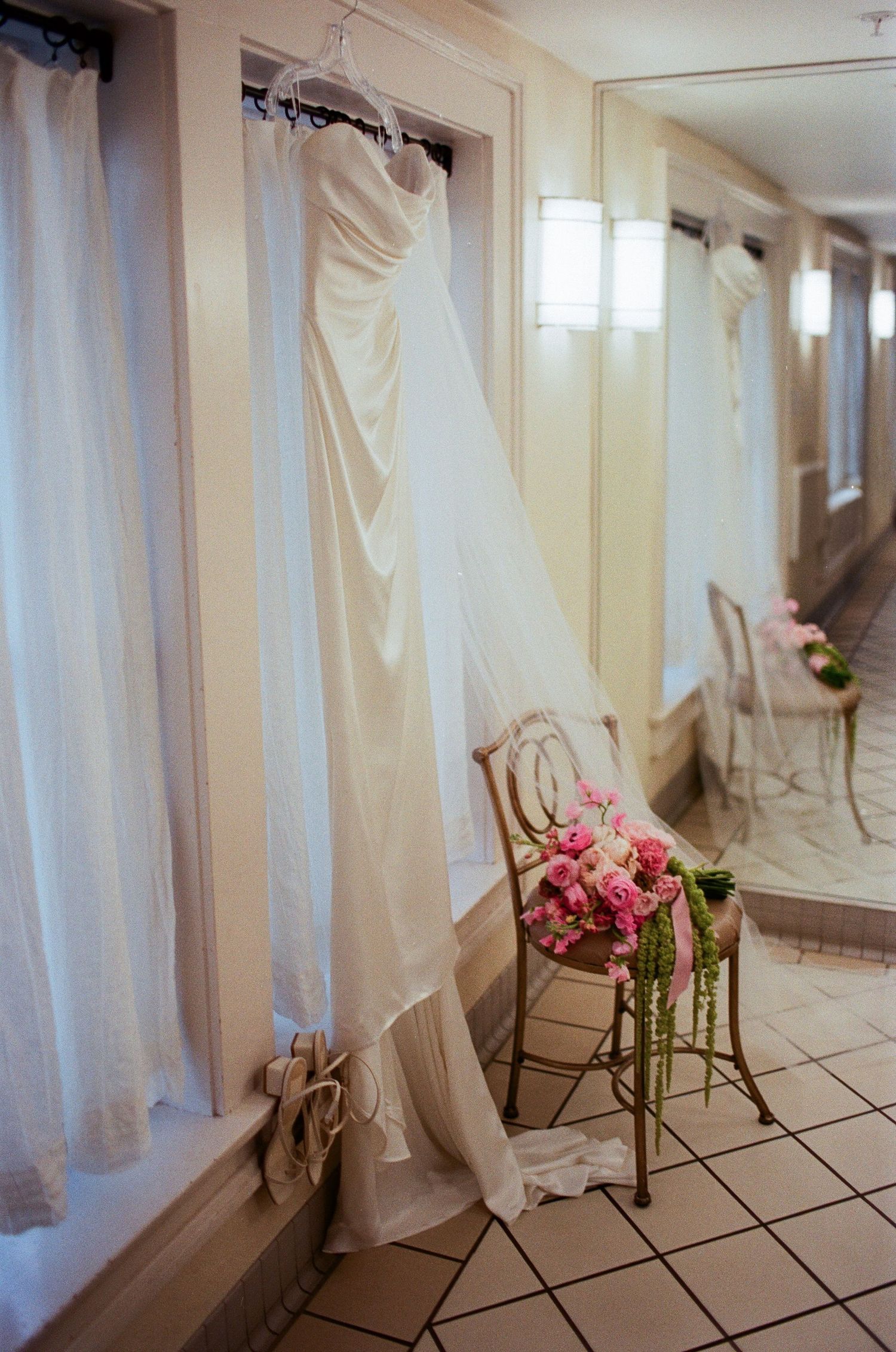 Wedding dresses hanging on display in a bridal boutique with pink floral accents.
