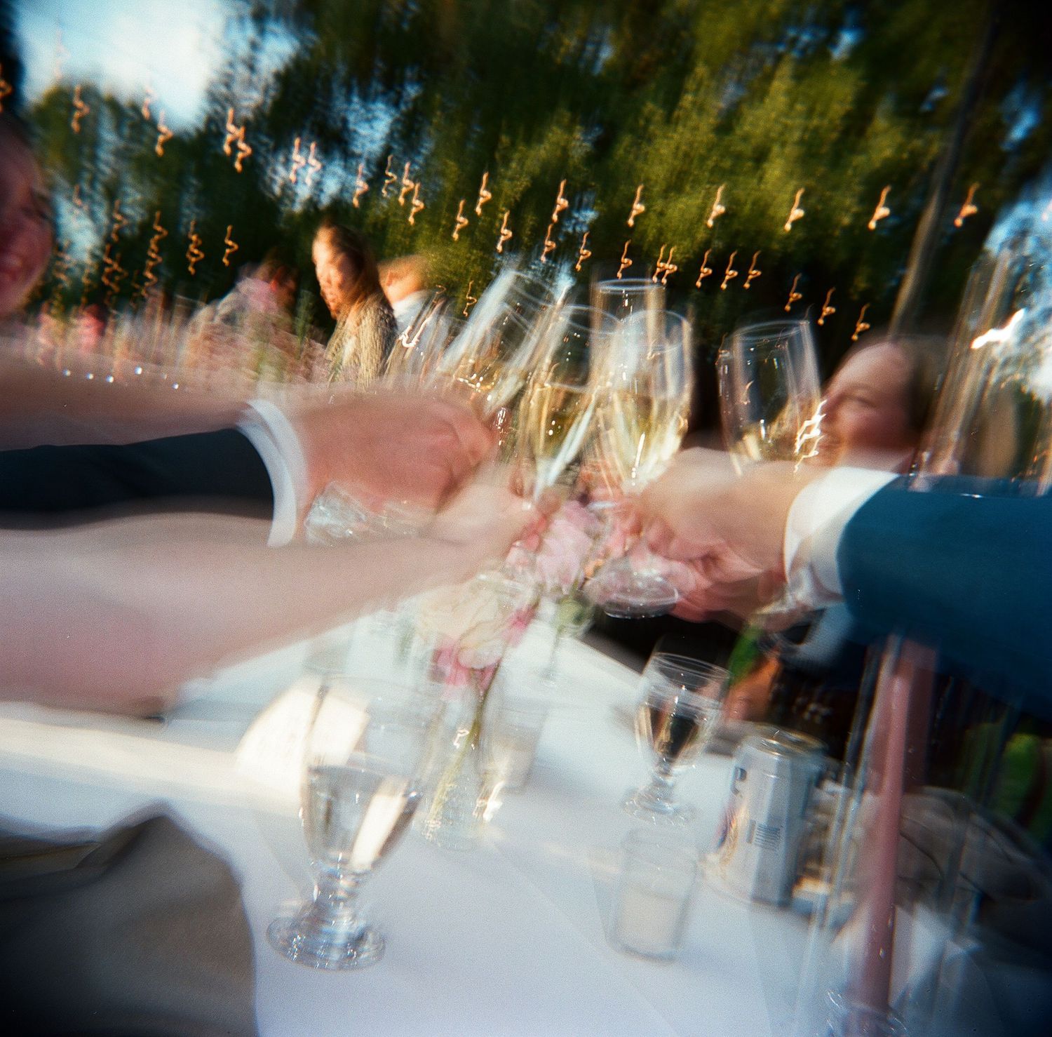 Champagne glasses clinking together in a celebratory toast with motion blur and sparkly lights.