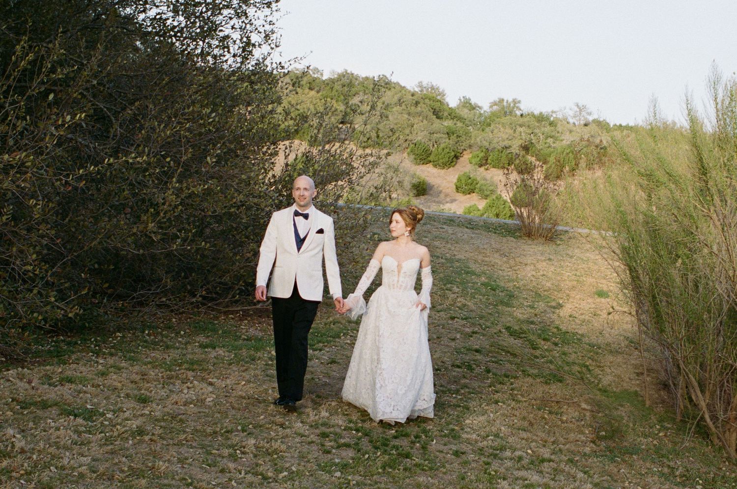Couple walking together on a scenic outdoor path surrounded by natural vegetation.