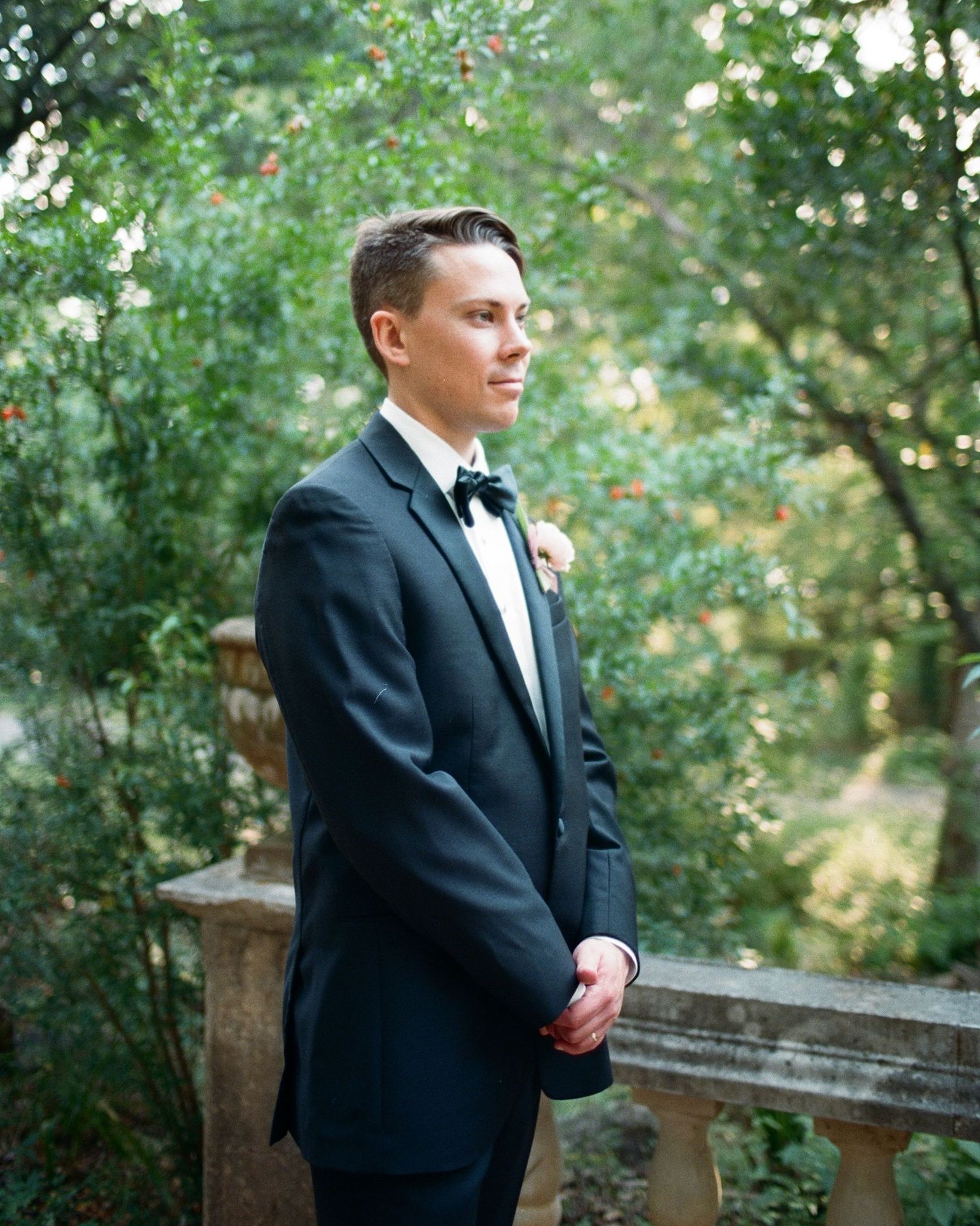 Formal wedding portrait session on garden path surrounded by greenery.