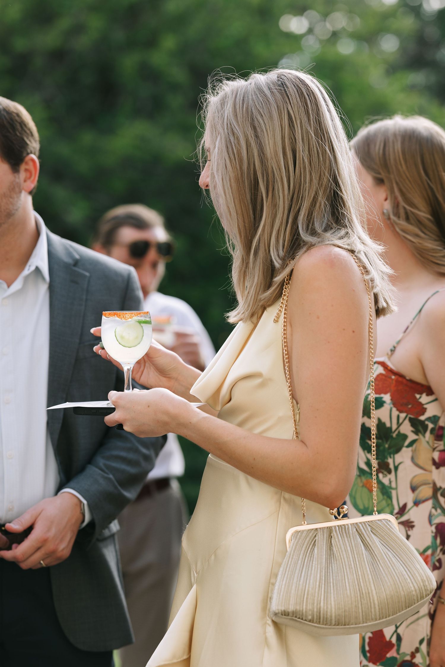 Party guests enjoy drinks and conversation at an elegant outdoor gathering.