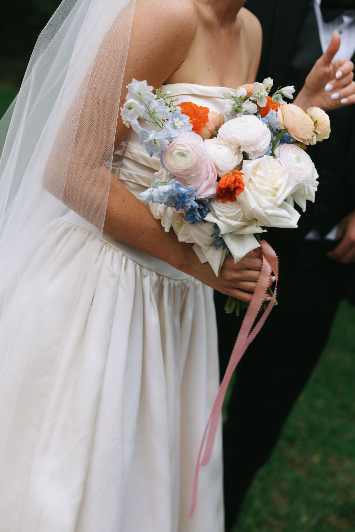Delicate bridal bouquet featuring white and coral flowers with flowing ribbons.