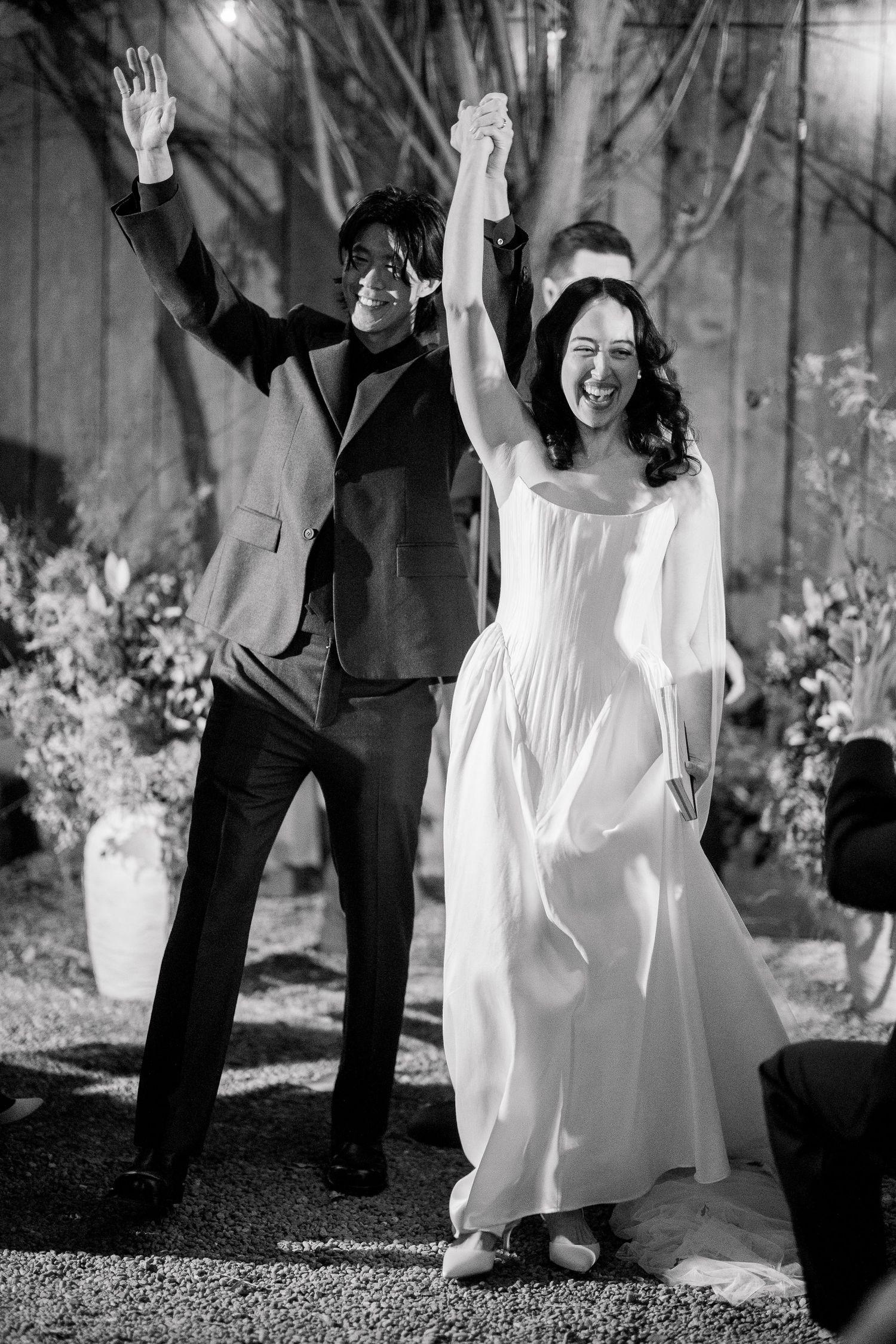 Wedding celebration with joyful dancing outdoors under string lights and trees.