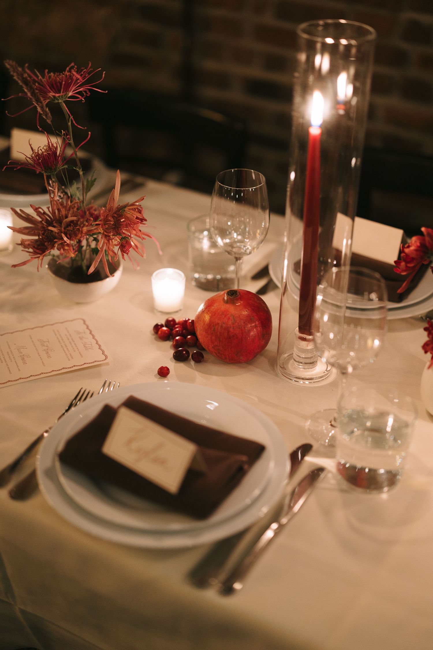 Elegant table setting with red apples, candles and white plates on crisp linens.