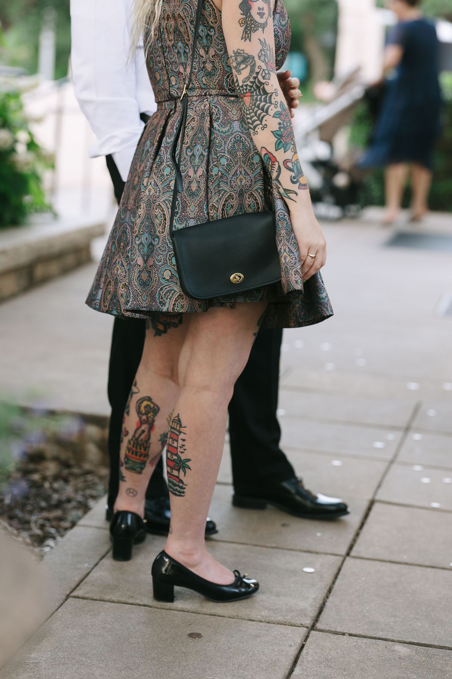 Close-up of floral dress and tattooed legs at an outdoor event.