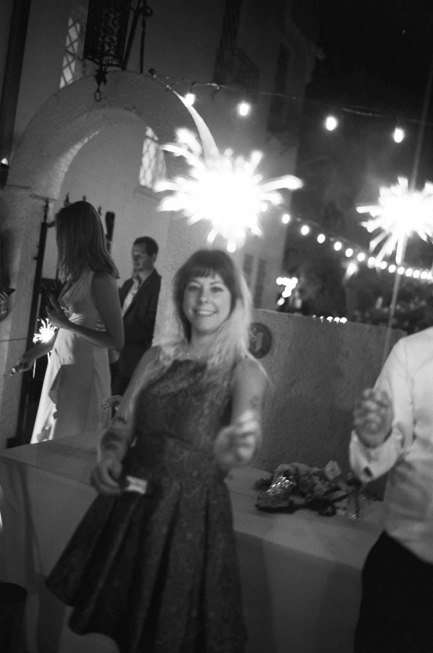 Wedding party members celebrate with sparklers creating a festive nighttime atmosphere.