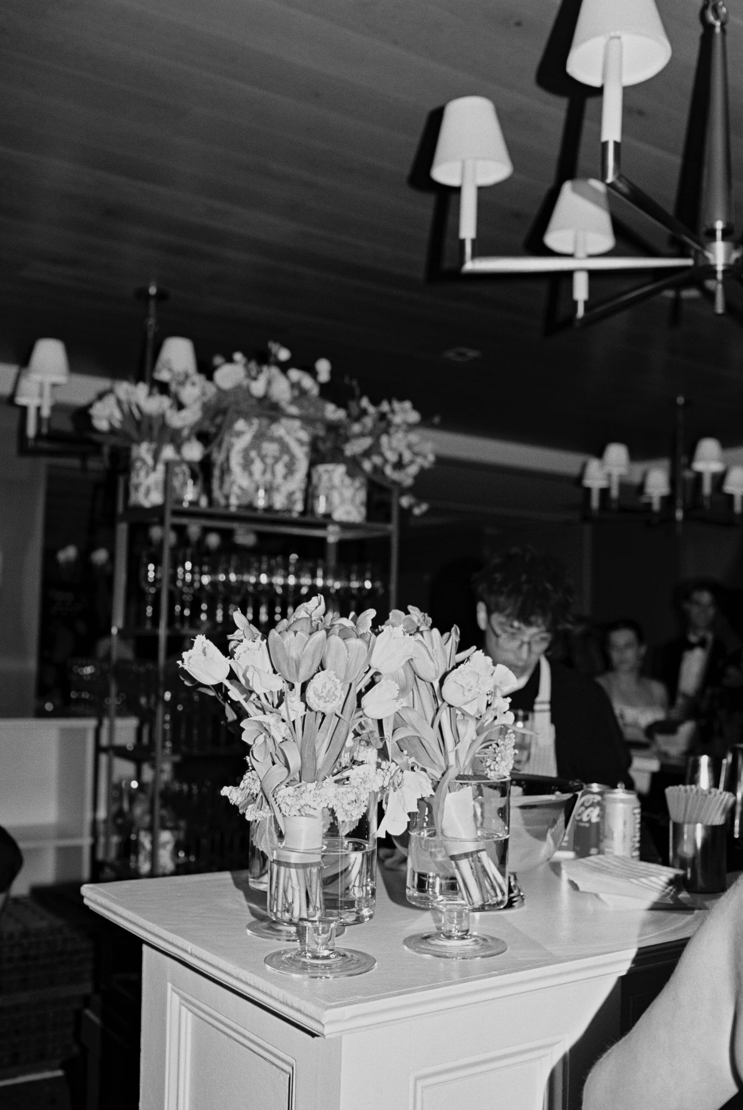 Black and white image of elegant floral centerpieces with white flowers in glass vases.