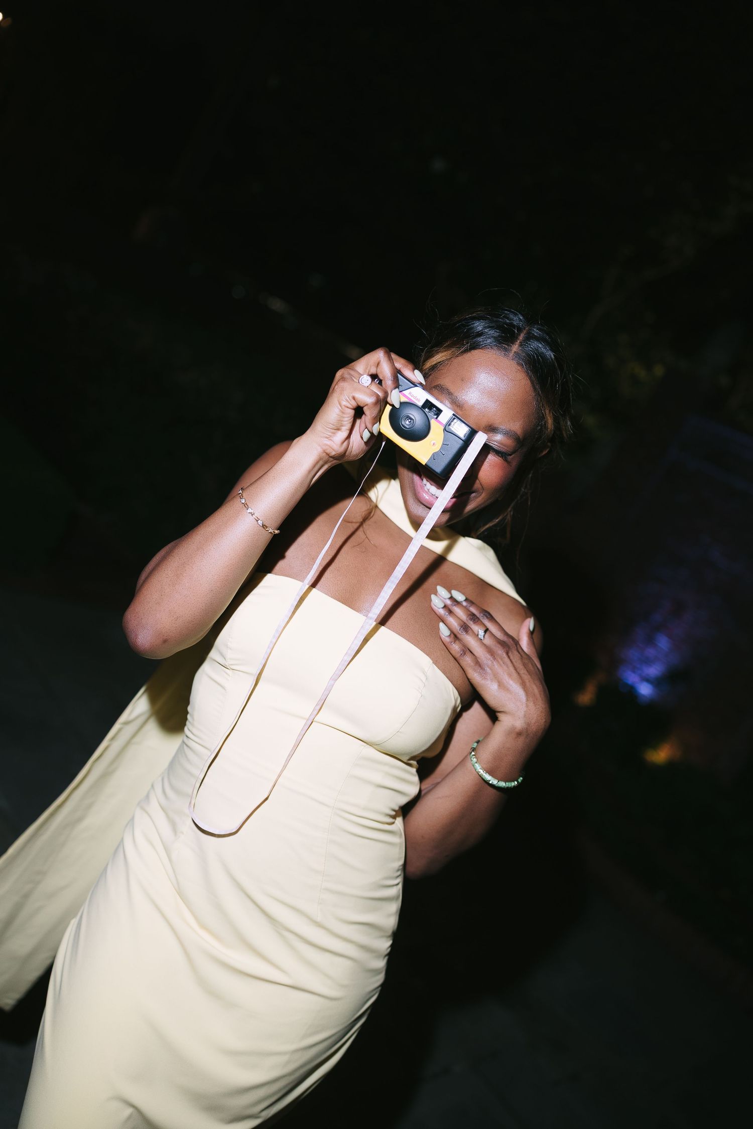 Person in cream colored outfit taking a drink at a nighttime event.
