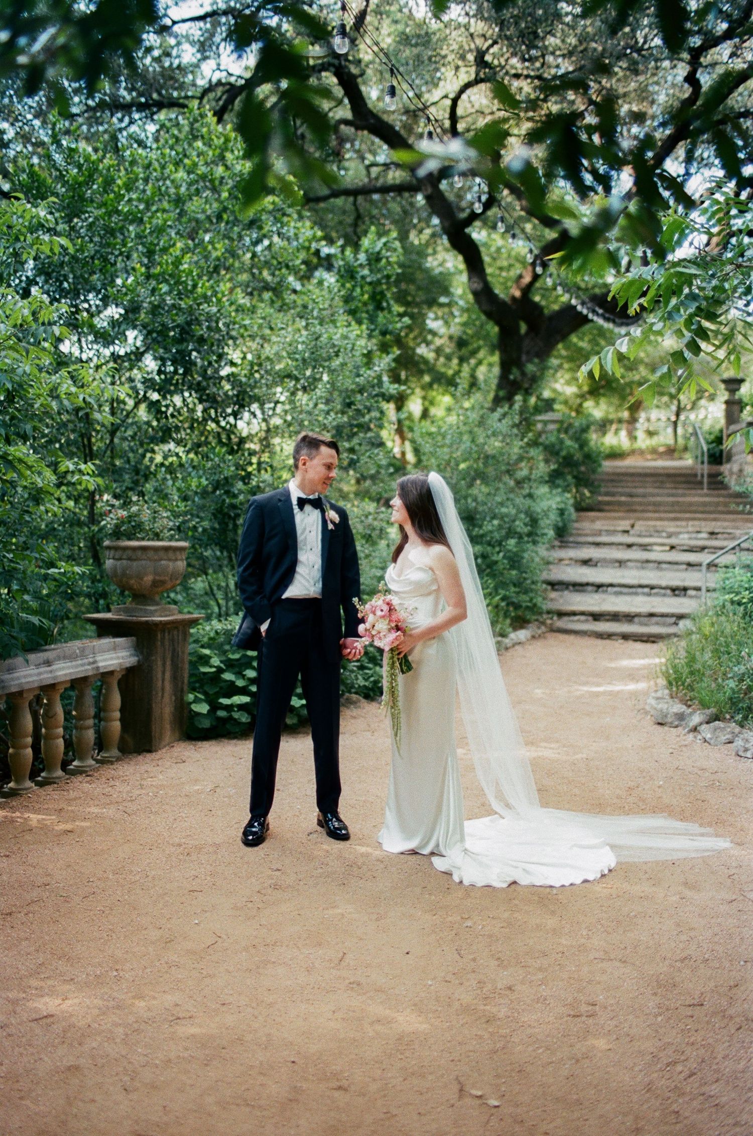 Garden wedding portrait session on a rustic dirt path surrounded by greenery.