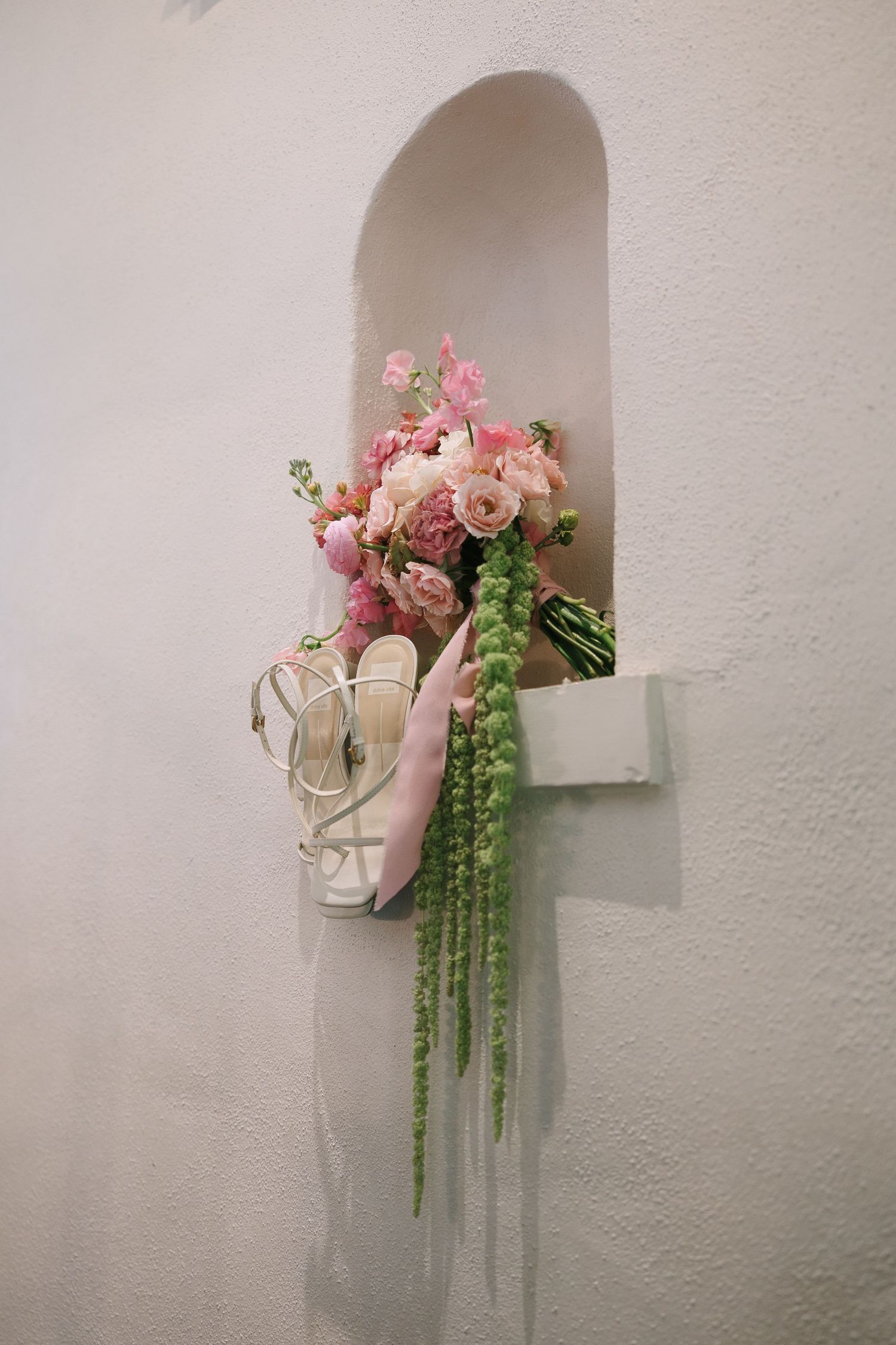 Pink roses and cascading greenery arranged in wall alcoves create a romantic display.