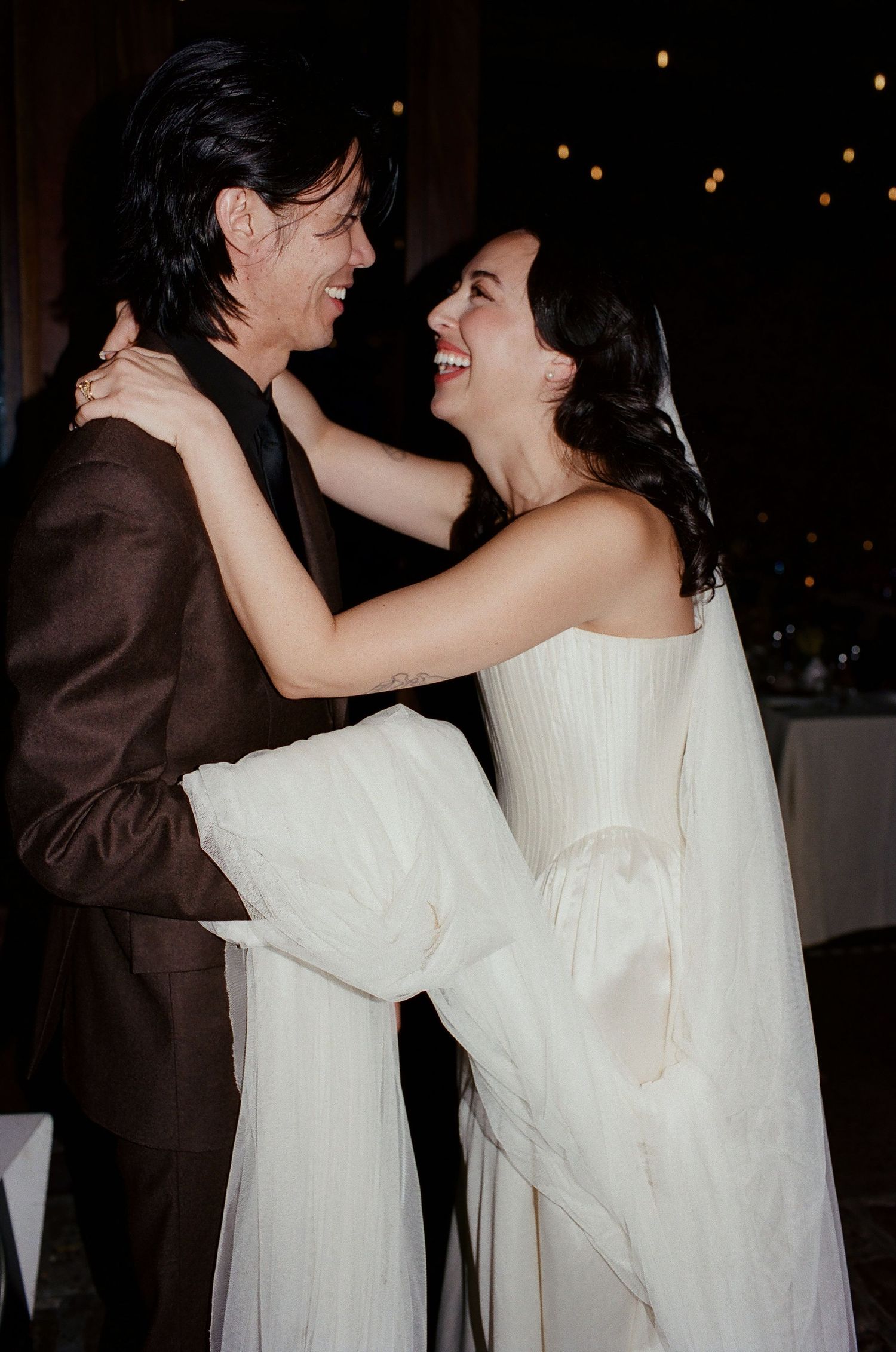 A couple in formal attire sharing an intimate dance moment, with the bride wearing a flowing white dress.