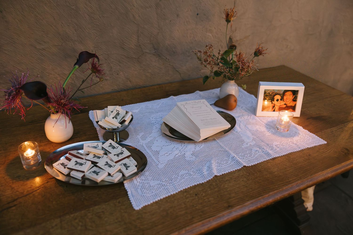 Wedding reception table settings with white linens, candles and decorative elements in warm lighting.