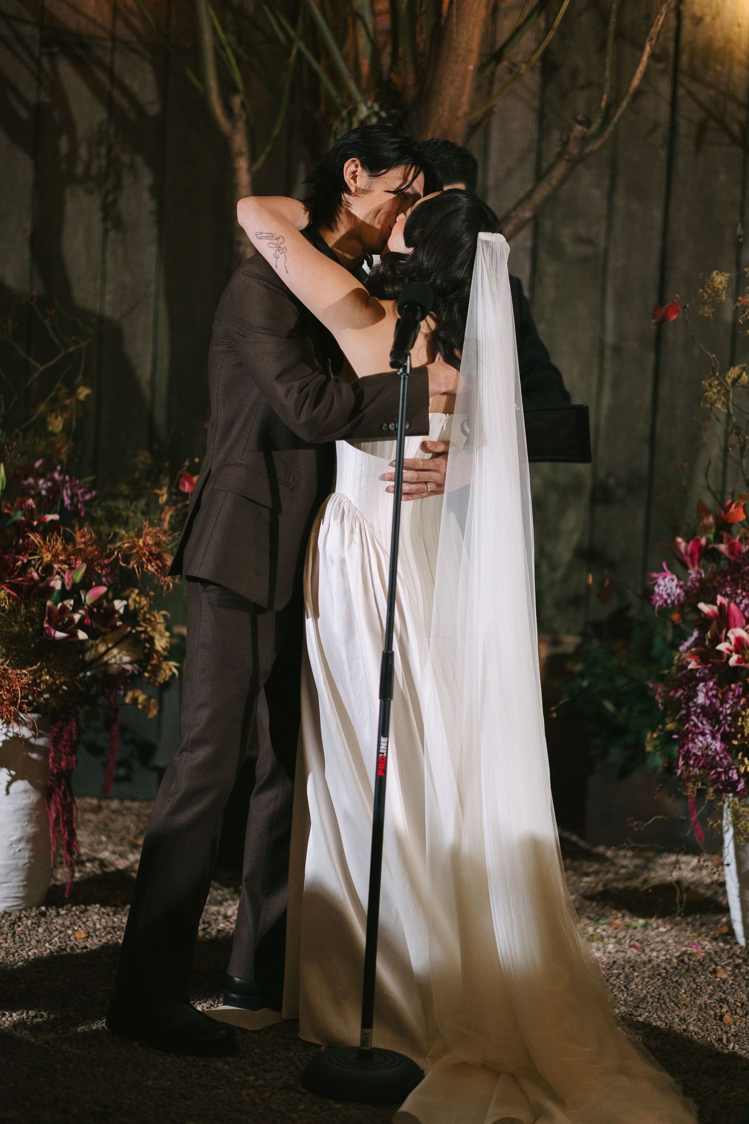 A romantic moment captured during an outdoor evening wedding ceremony under string lights.