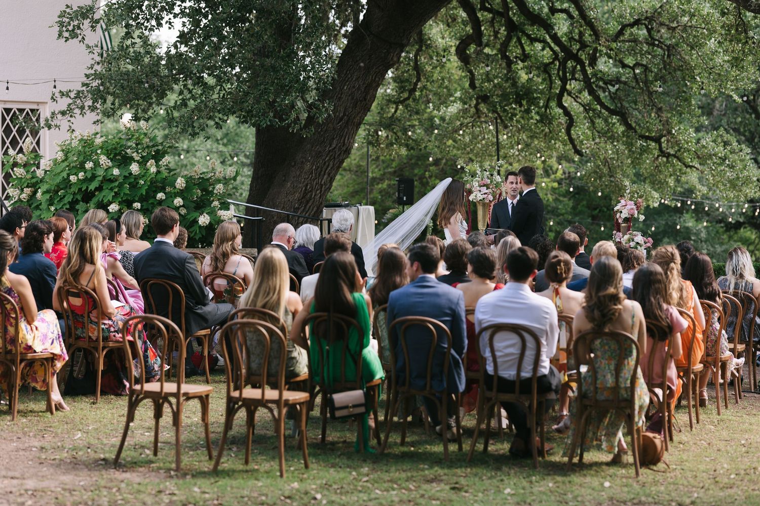 Panoramic shot of wedding guests seated in rows during outdoor ceremony.